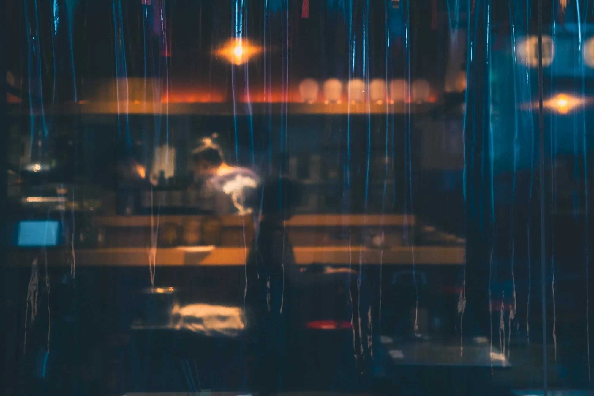 Print AD-0002. A figure behind a translucent curtain and hanging lamps.