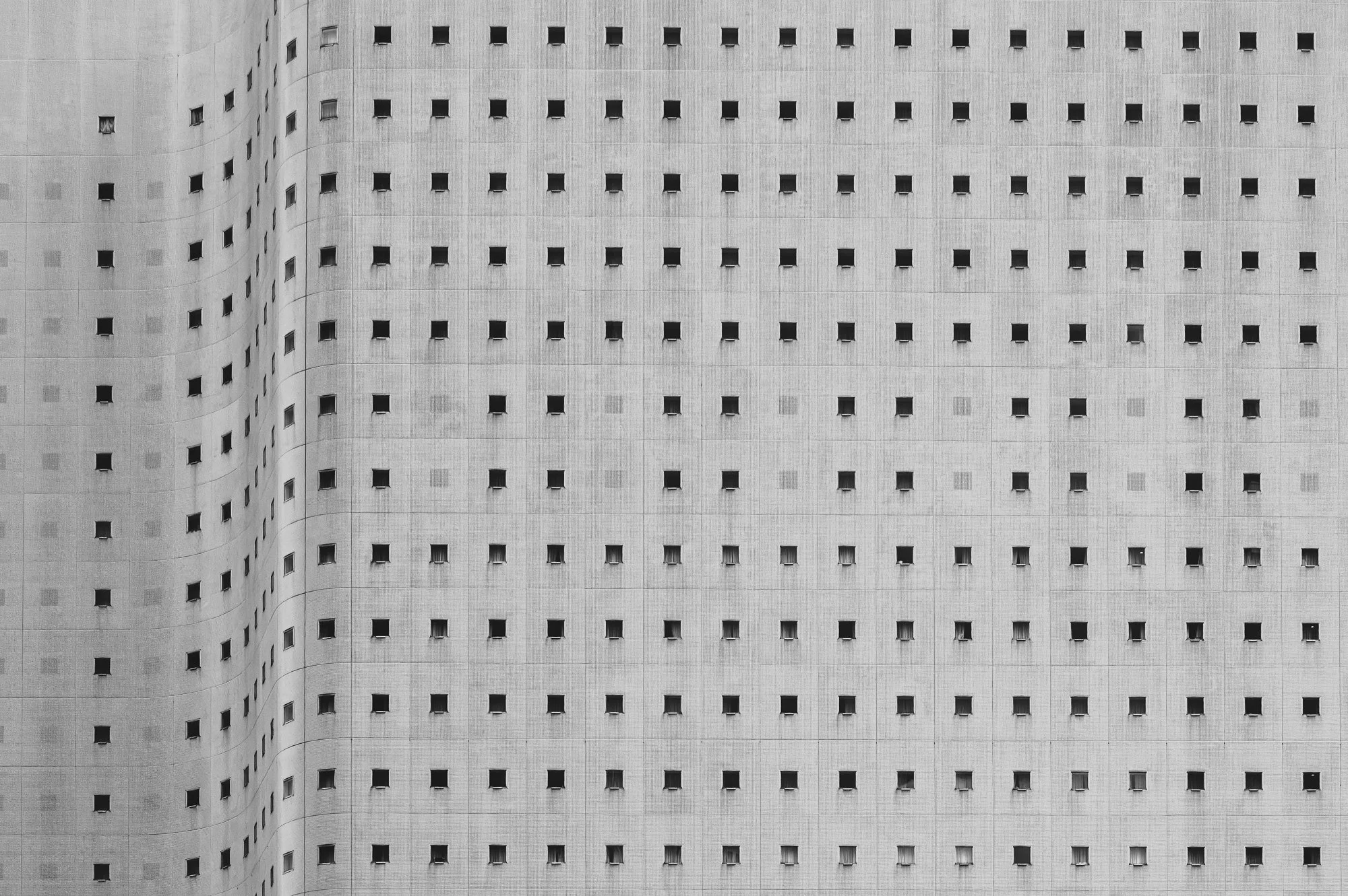 Print AD-0013. Repeating square windows across a curved concrete facade.