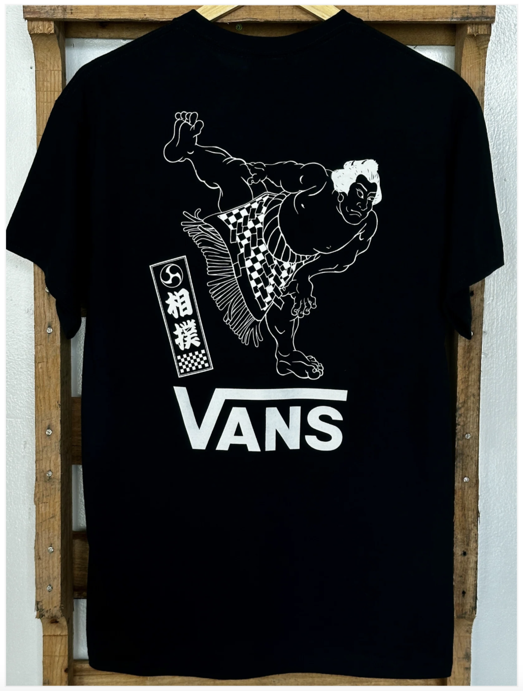 Black Vans T-shirt featuring a white graphic illustration of a sumo wrestler in motion with Japanese characters and the Vans logo.