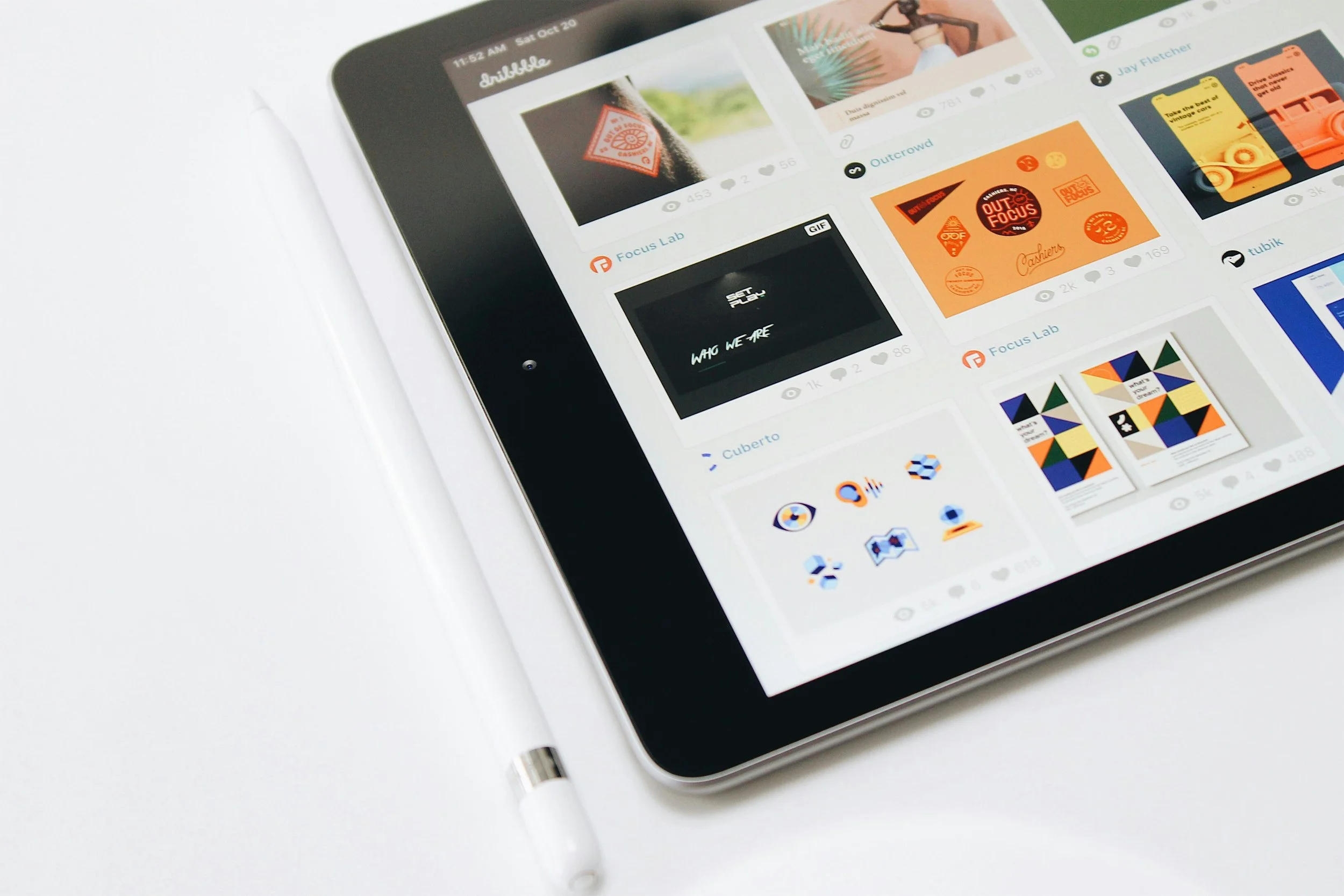 Close-up of a tablet screen showing design portfolio thumbnails on Dribbble