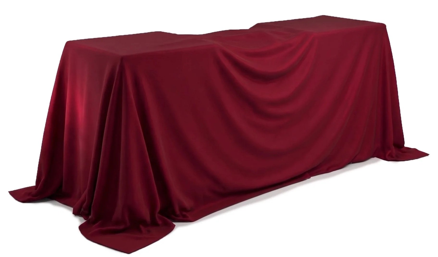 An empty table covered with a red velvet cloth that drapes down to the floor.