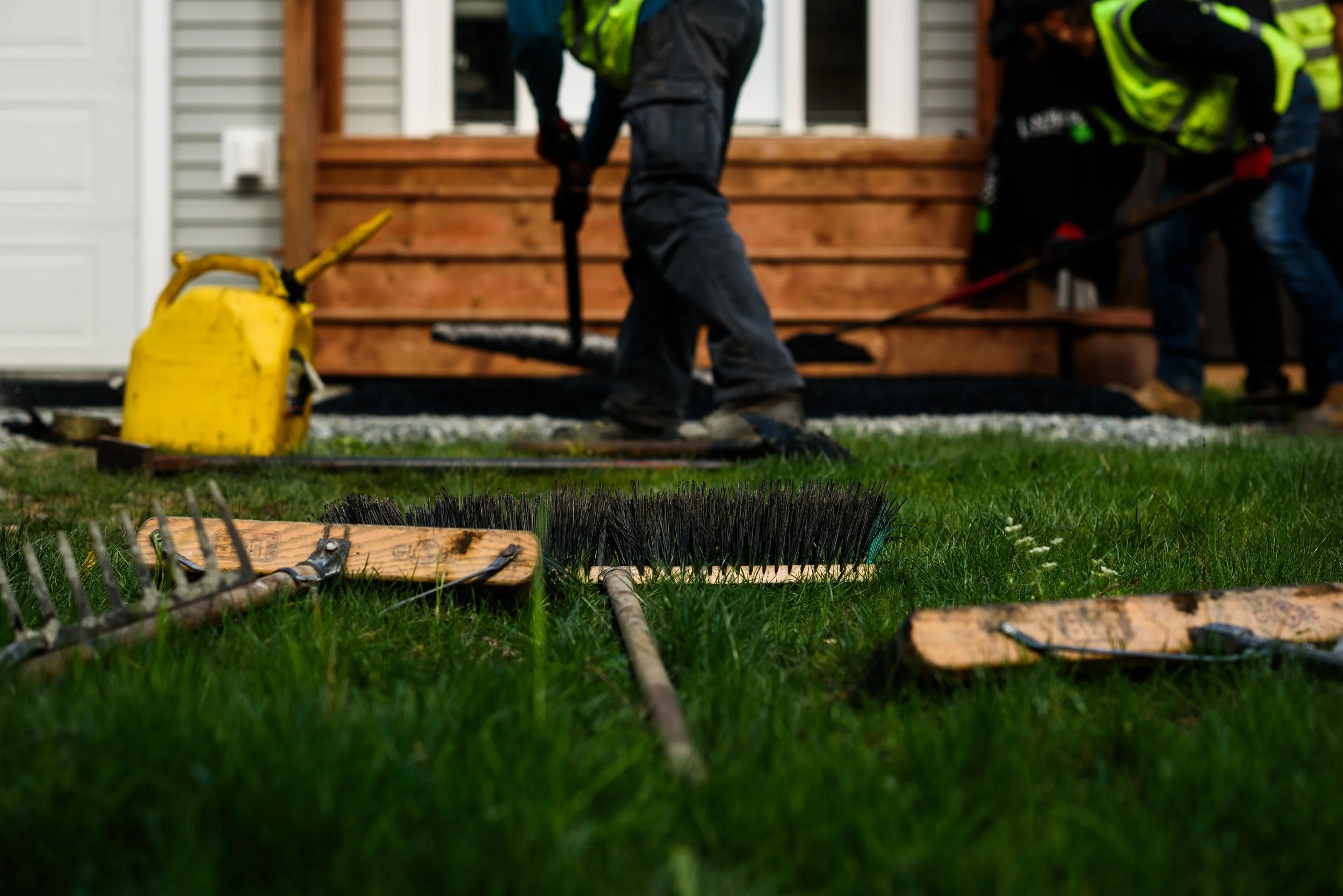 People installing a wooden deck outside a house, with tools and equipment in the foreground.