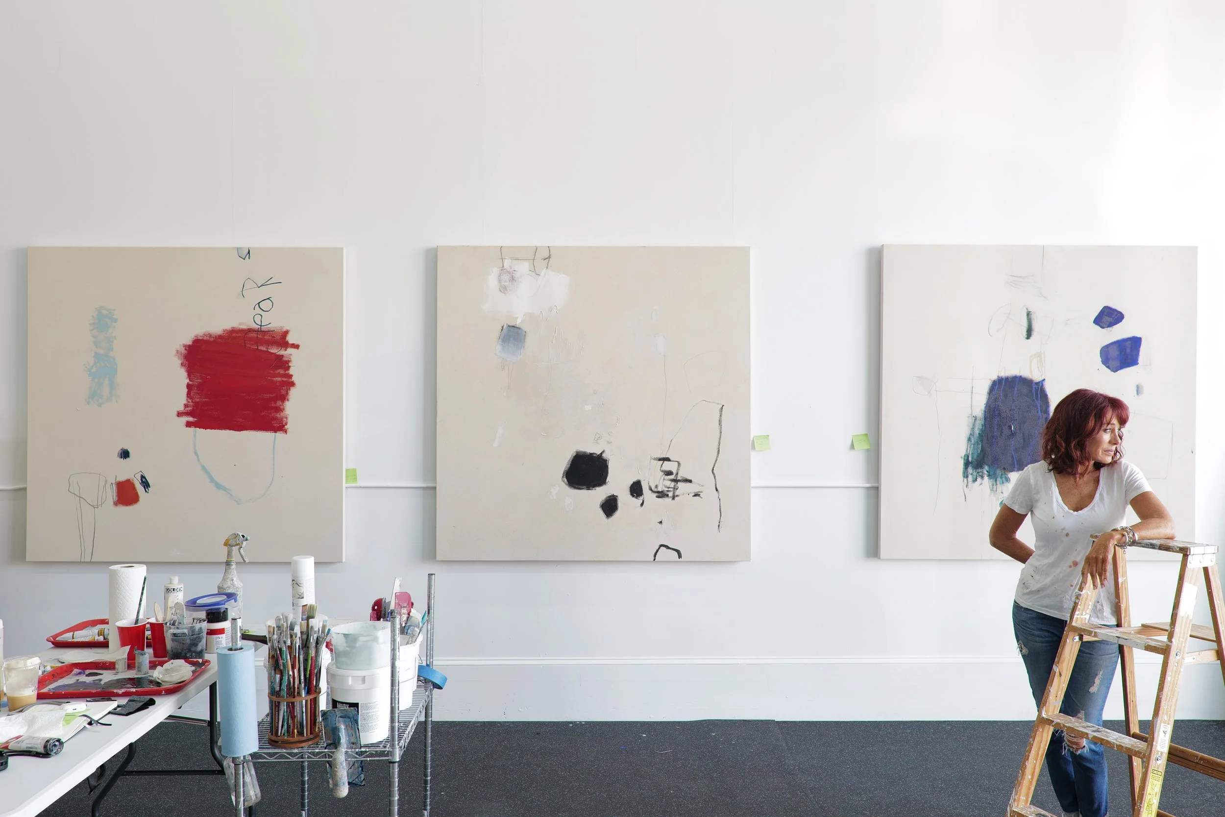 Chris Brandell, intuitive abstract artist in her studio on Marco Island standing in front of 3 paintings