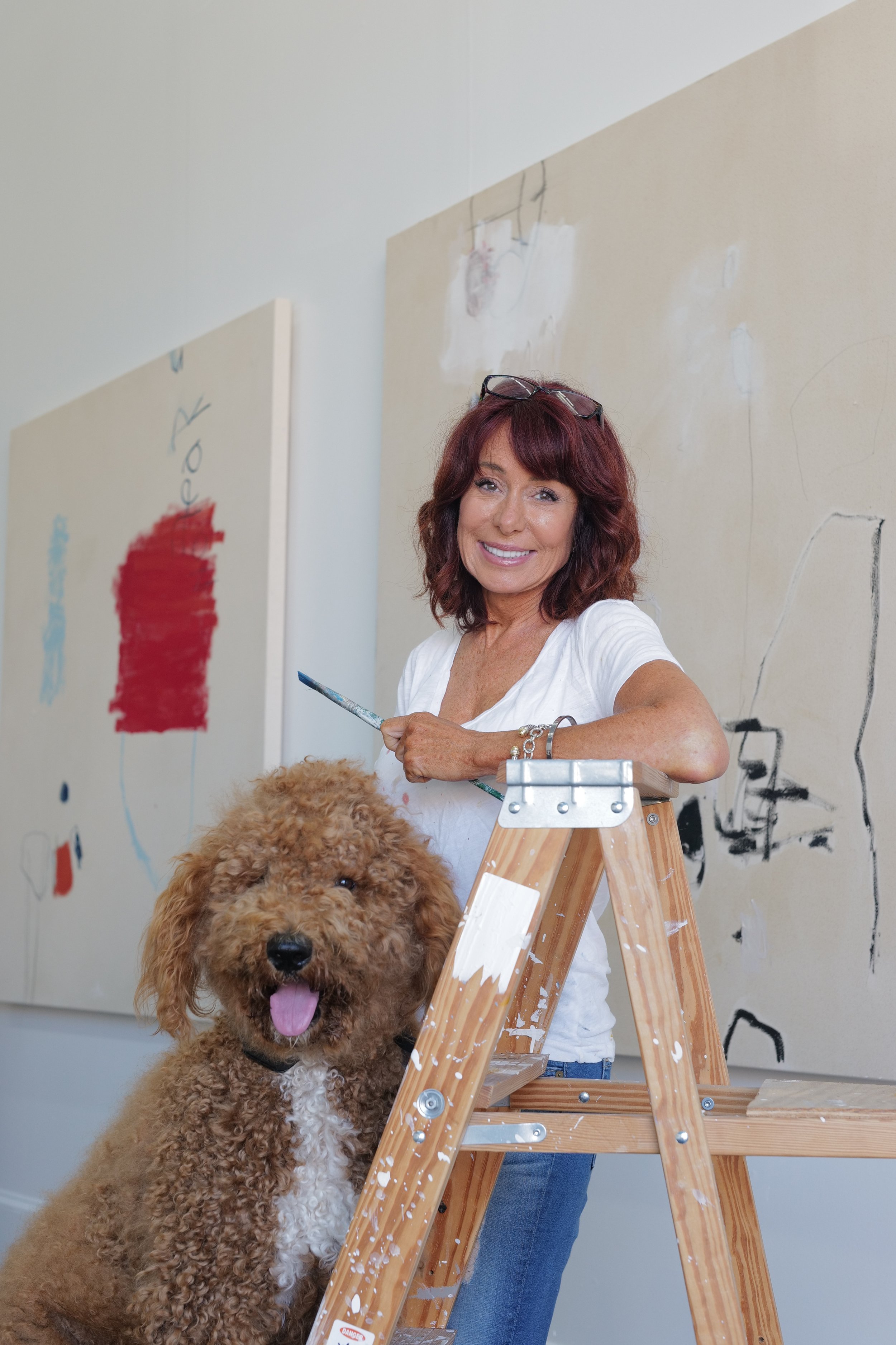 Chris Brandell with the studio dog, Sam, leaning on a ladder in Studio 7 on Marco island