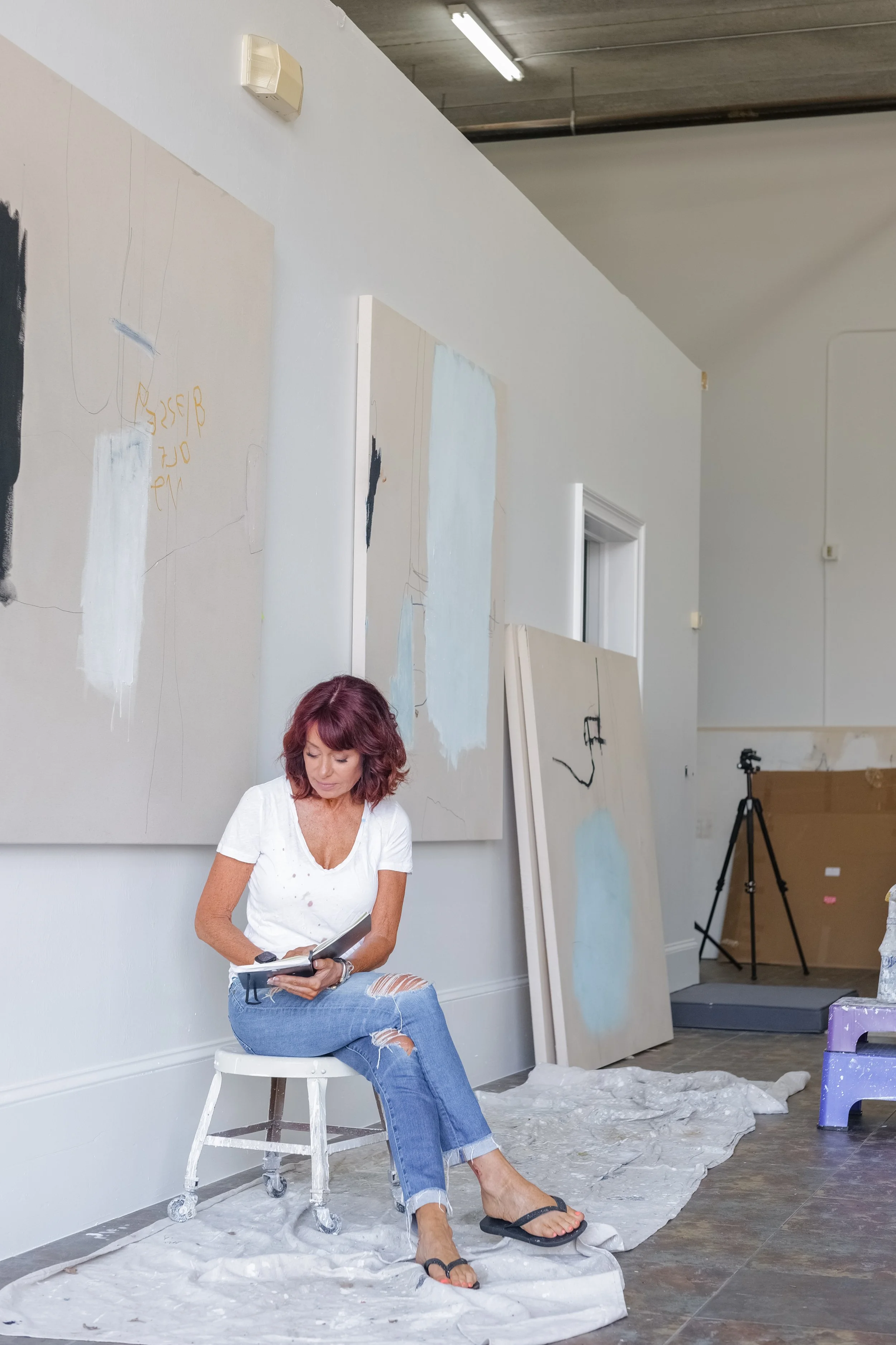 Chris Brandell sitting in her light filled studio reading from her journal