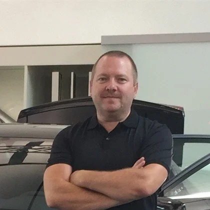 Professional portrait of a man in a suit and tie against a black background.