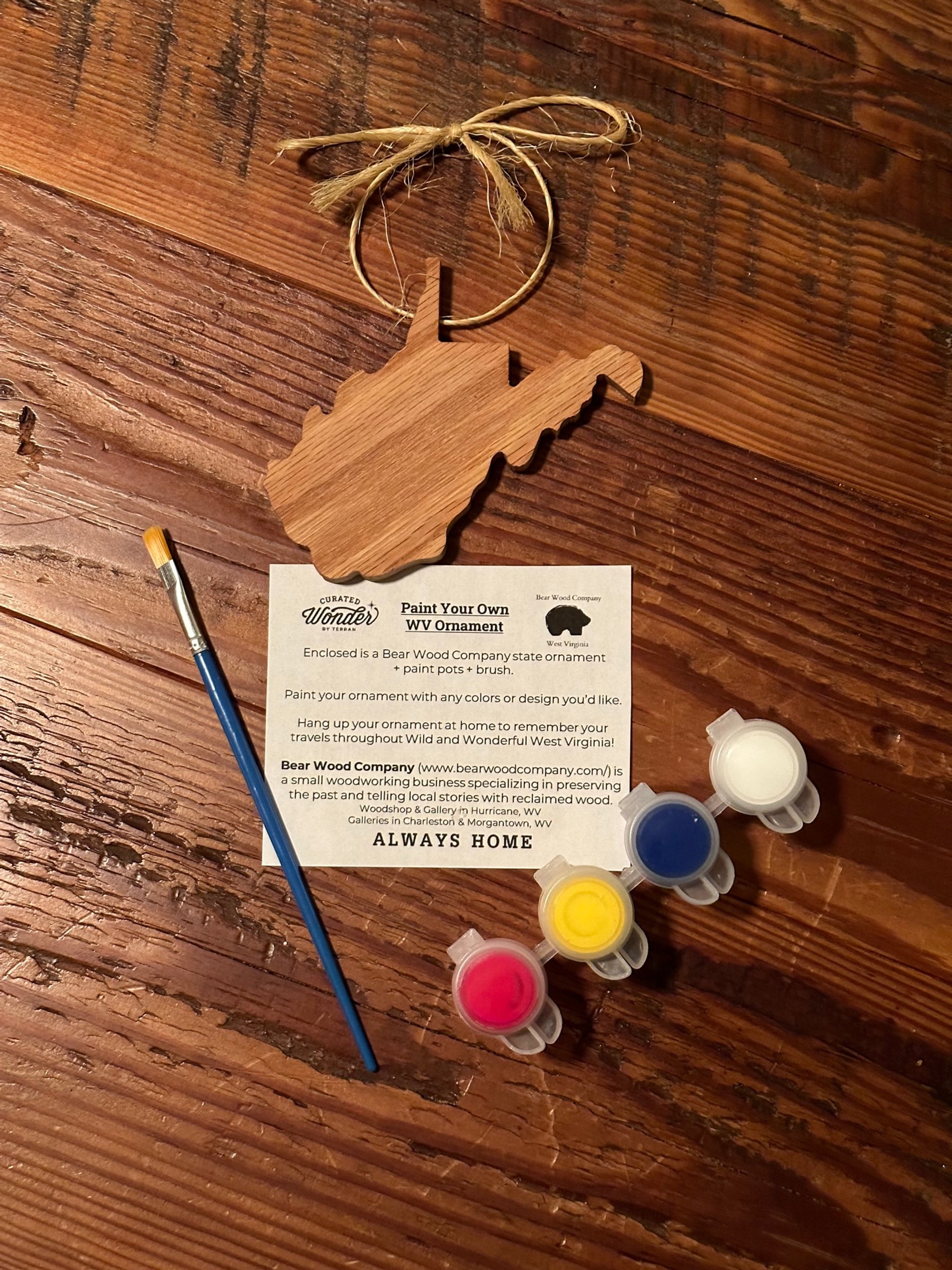 A wooden WV ornament inside the Country Roads Explore WV Day Trips Kit