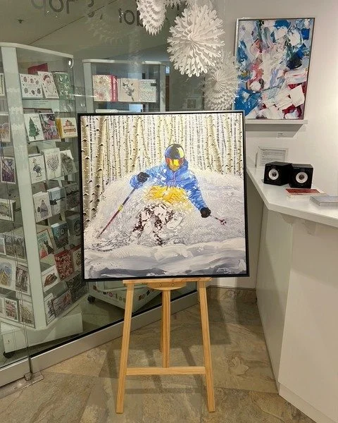 Right of Way - Print on Board - 40x40 - Now available at the Museum London  Shop (pictured here). 

A dynamic winter scene of a skier carving confidently through deep powder, framed by a quiet forest of pale birch trees. Bold colour contrasts and swe
