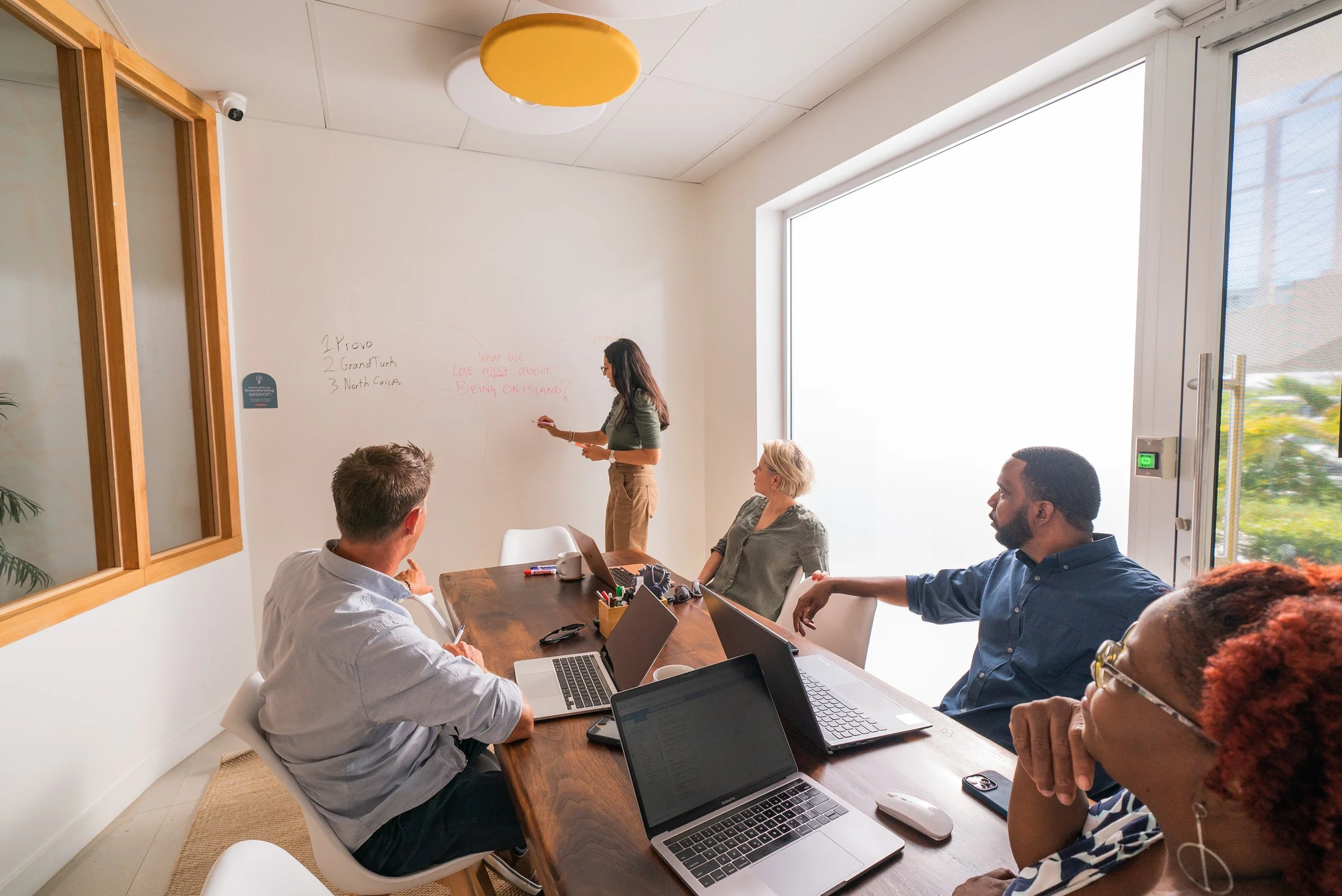 Team meeting with laptops and a whiteboard at On Island coworking space in Grace Bay, Providenciales