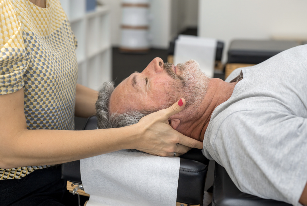 A person receiving chiropractic or neck adjustment treatment from a chiropractor in an office setting.