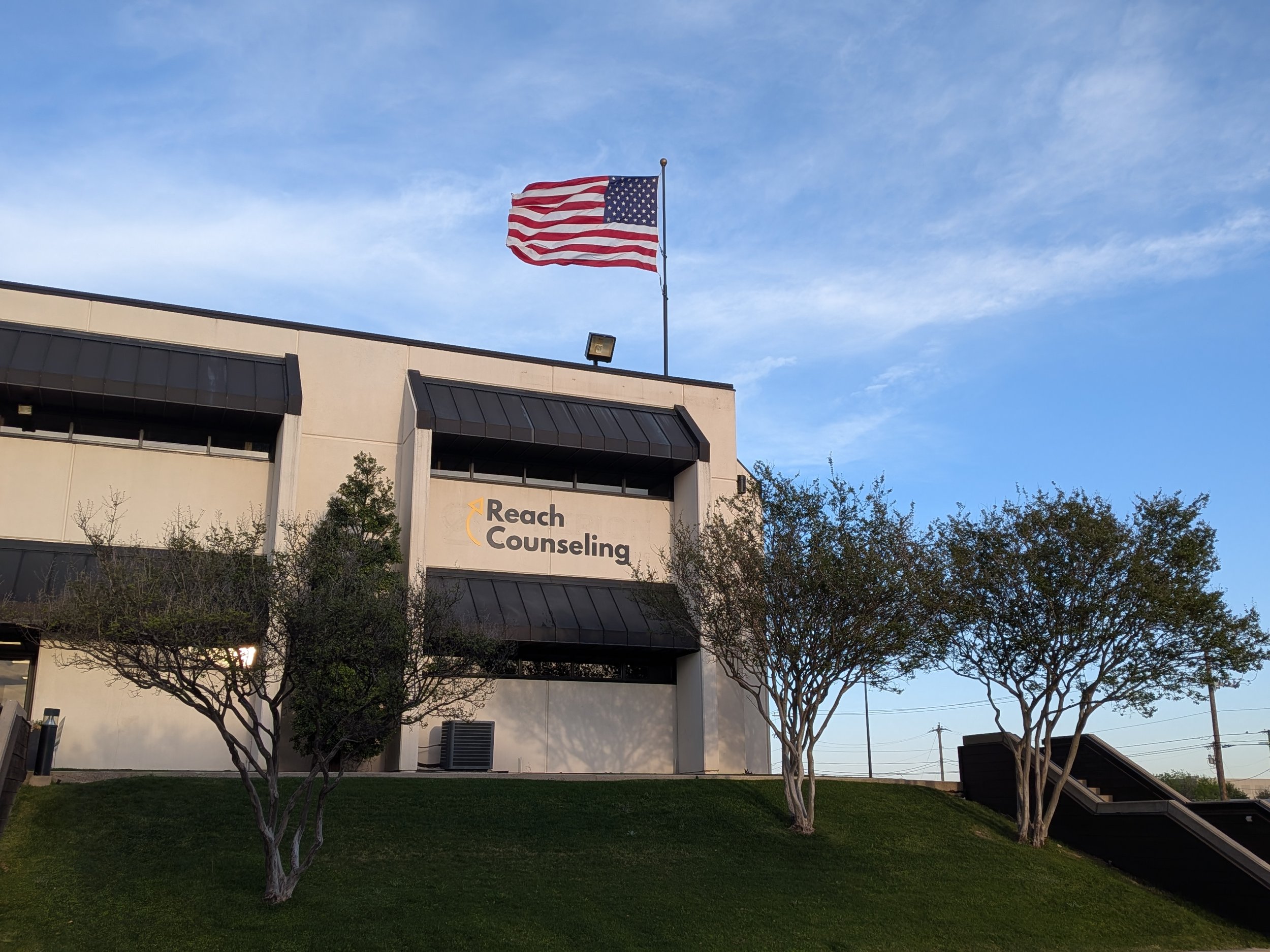 Outside of a cream office building with Reach Counseling on wall