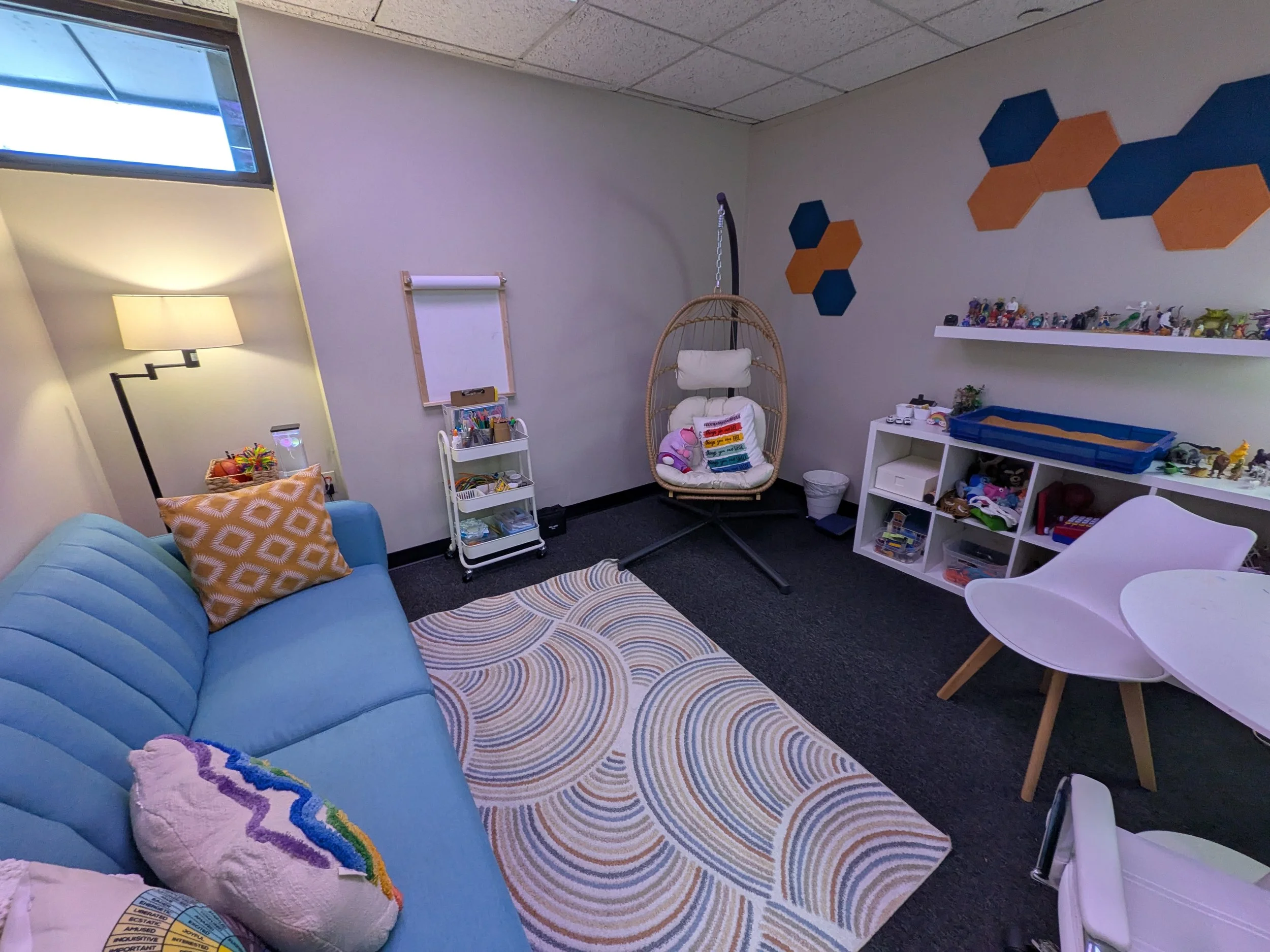 Room with a blue couch and swing chair with sand tray
