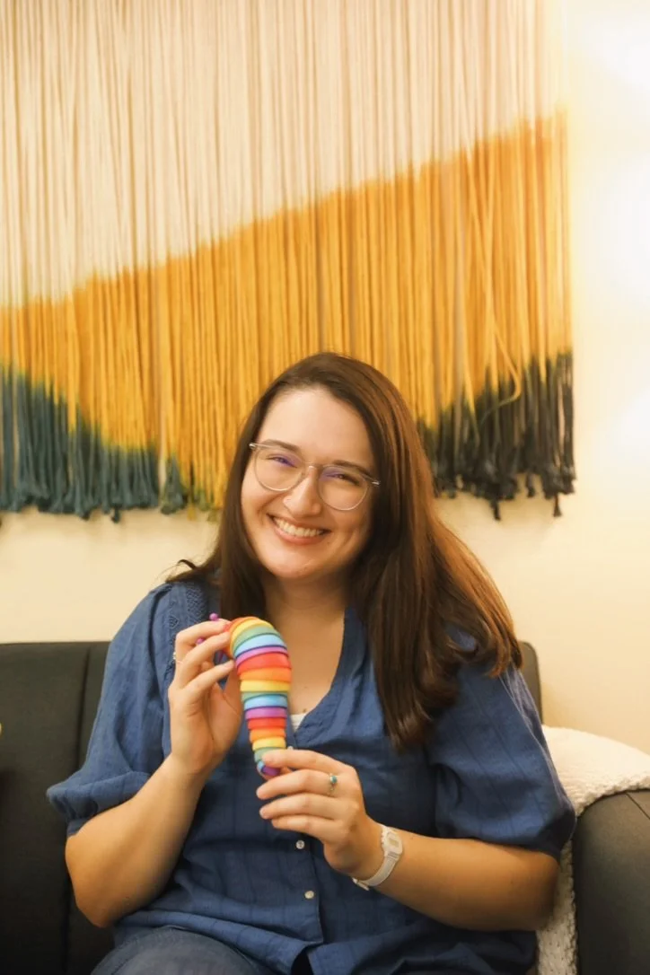 Therapist with long hair smiling and holding a fidget