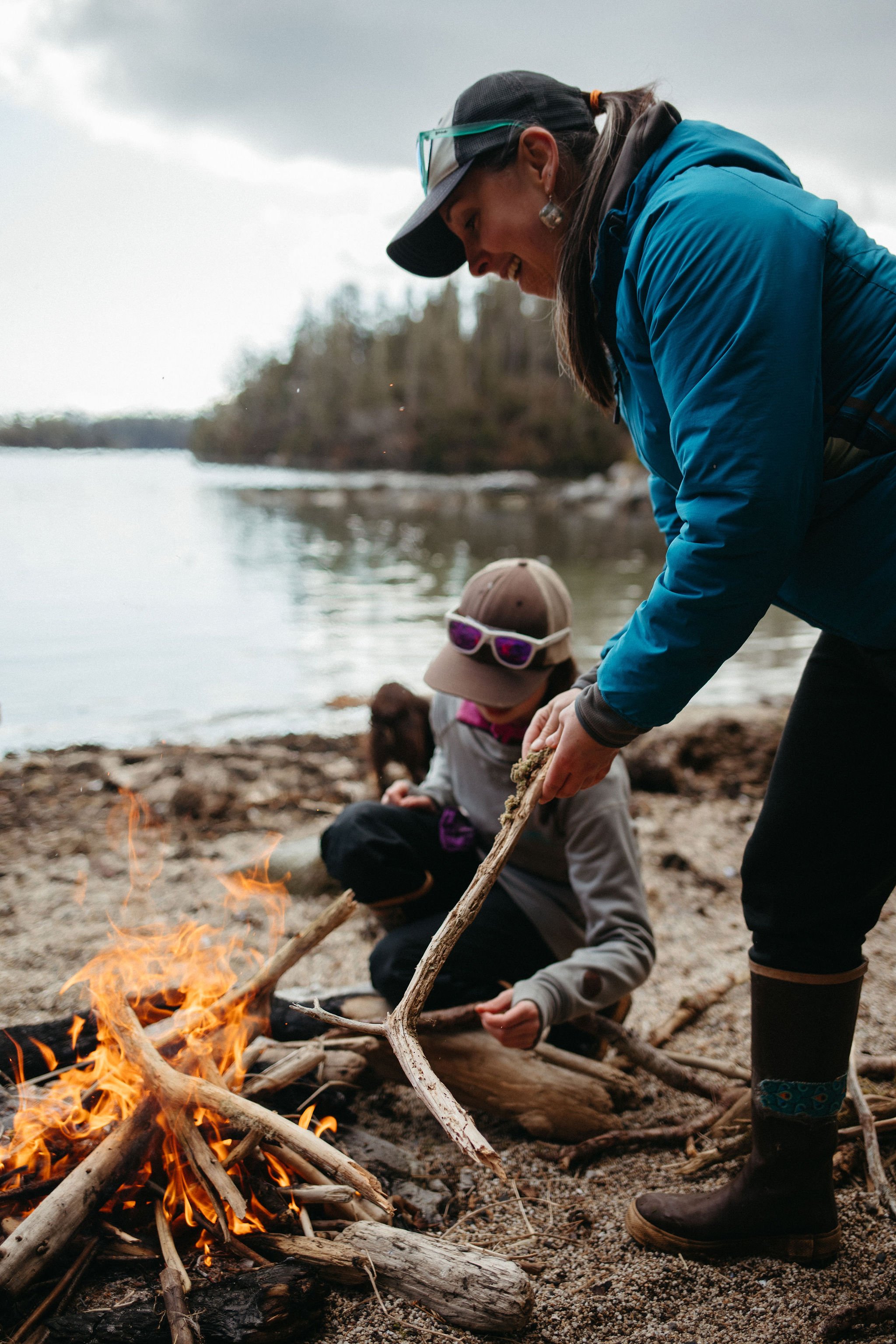 Jeren building a fire and smiling building a fire with a young girl on the beach.