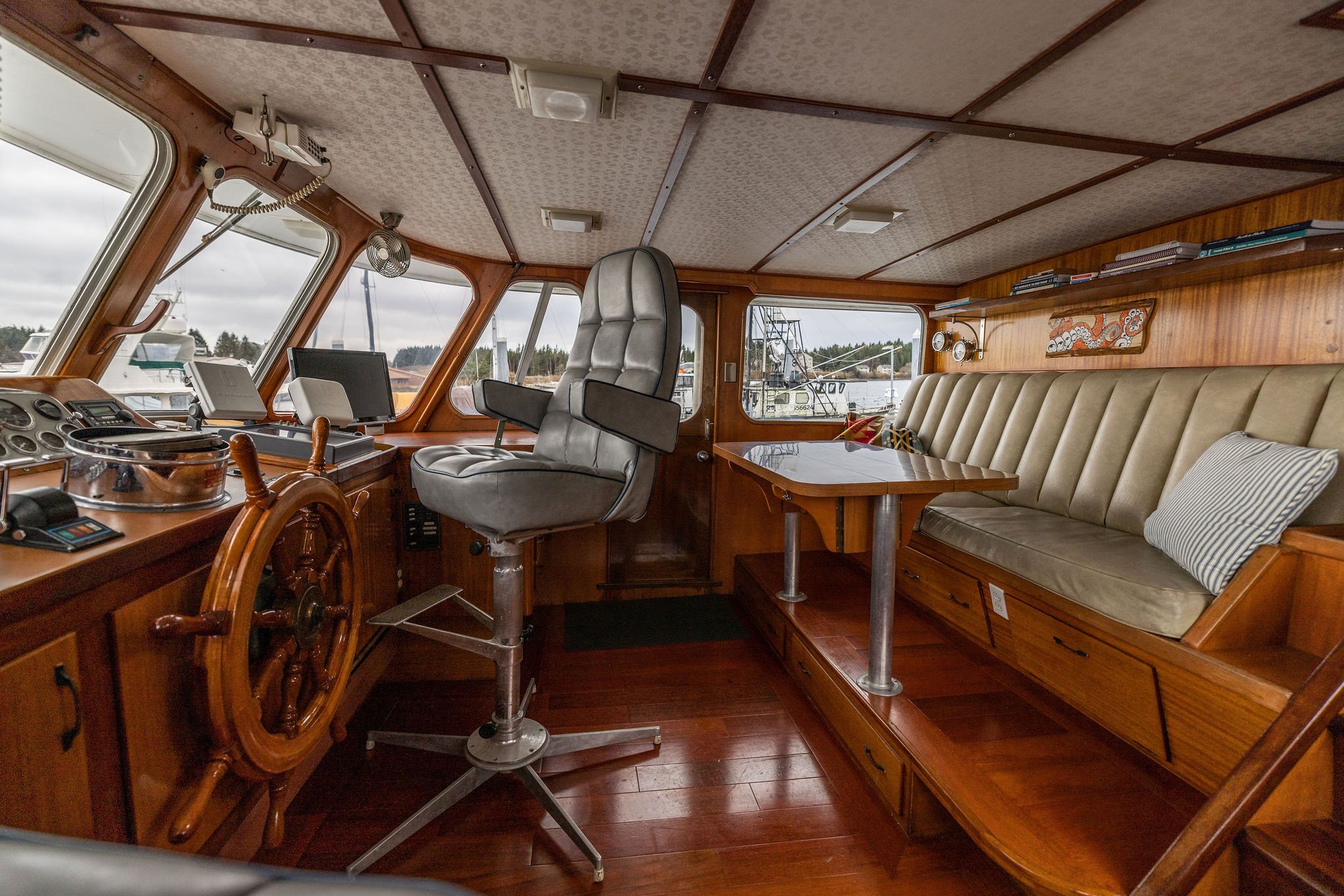 Wheelhouse with settee, captains chair and ships wheel.