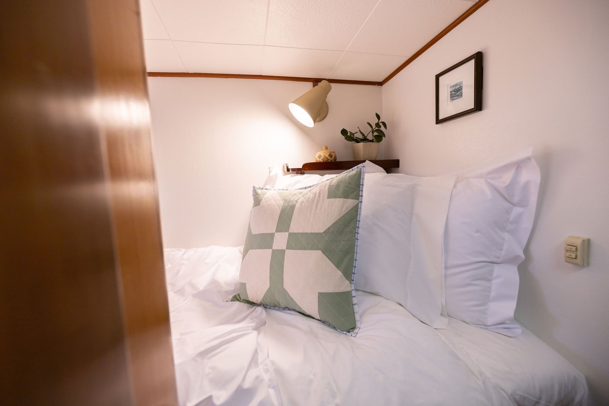One bunk in the Bunkroom with pillows, linens and light.