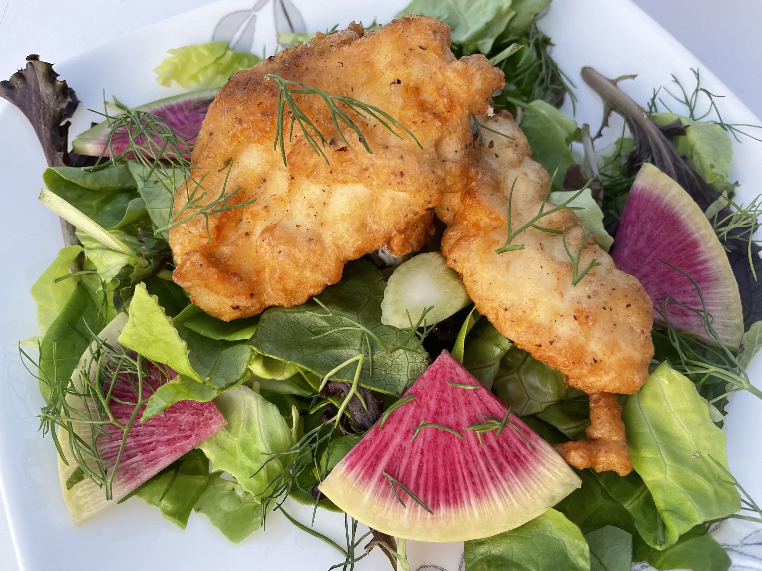 A colorful salad topped with lightly breaded halibut.