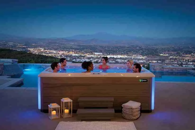 Photo of six adults in a spa bath at night with a view over a cityscape