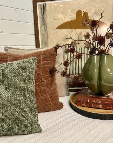 Stylish cushions on a lounge with olive colored vase and dried flowers