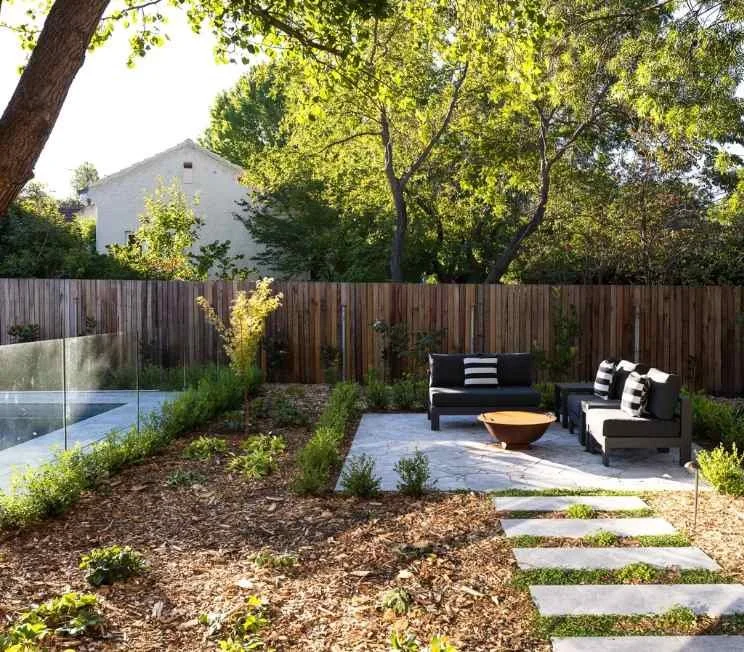 Outdoor mulched garden with concrete steps and separate fire pit area with lounge