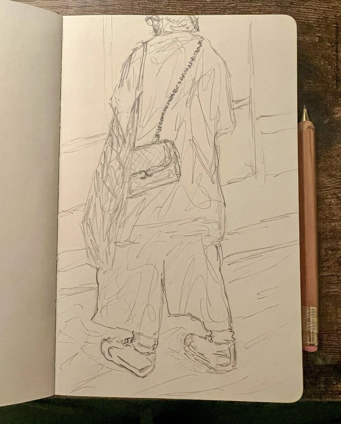 Pencil sketch of a woman standing indoors, looking out a glass window at the street. She is wearing modern clothing, with a crossbody purse and a tote bag.