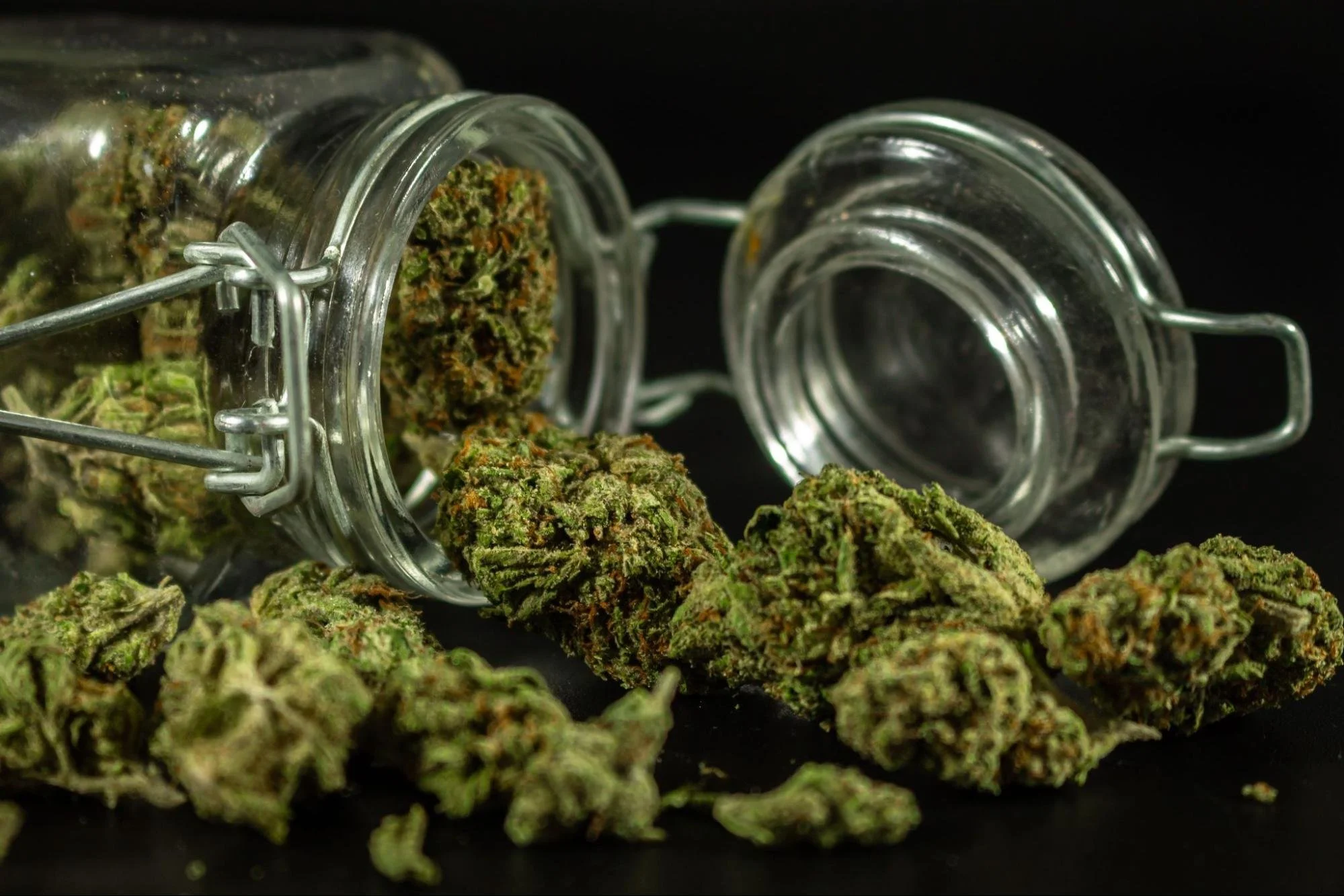 An image of cannabis flower spilling out of a glass jar. Source - Pexels