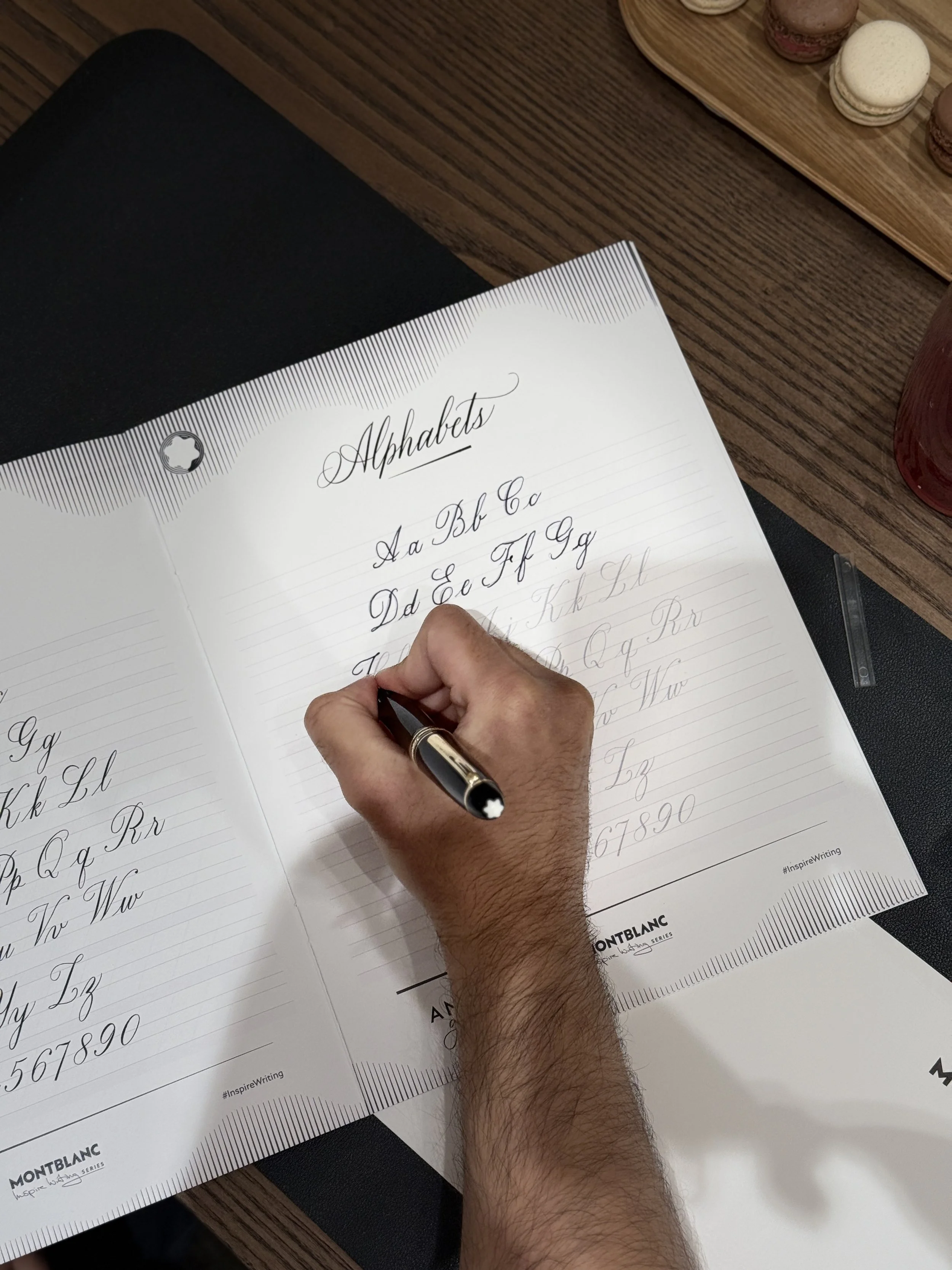 Person practicing calligraphy on an alphabet practice sheet with cursive letters.