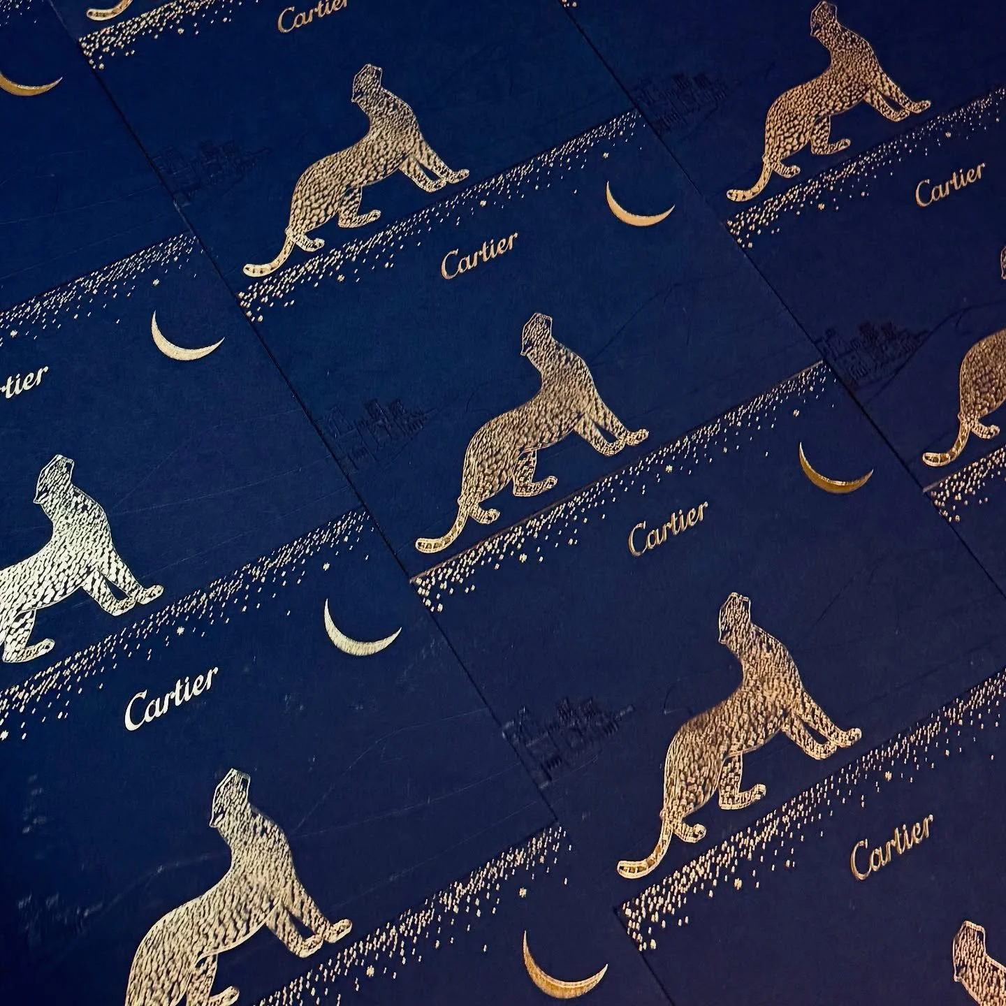 Multiple blue boxes with gold designs featuring a leopard, a crescent moon, and the word "Cartier".