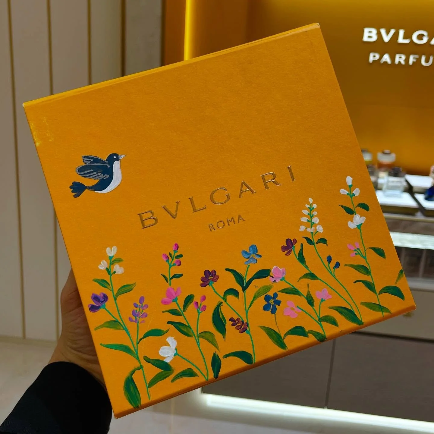 A yellow Bvlgari Roma perfume box with a bird and floral design.