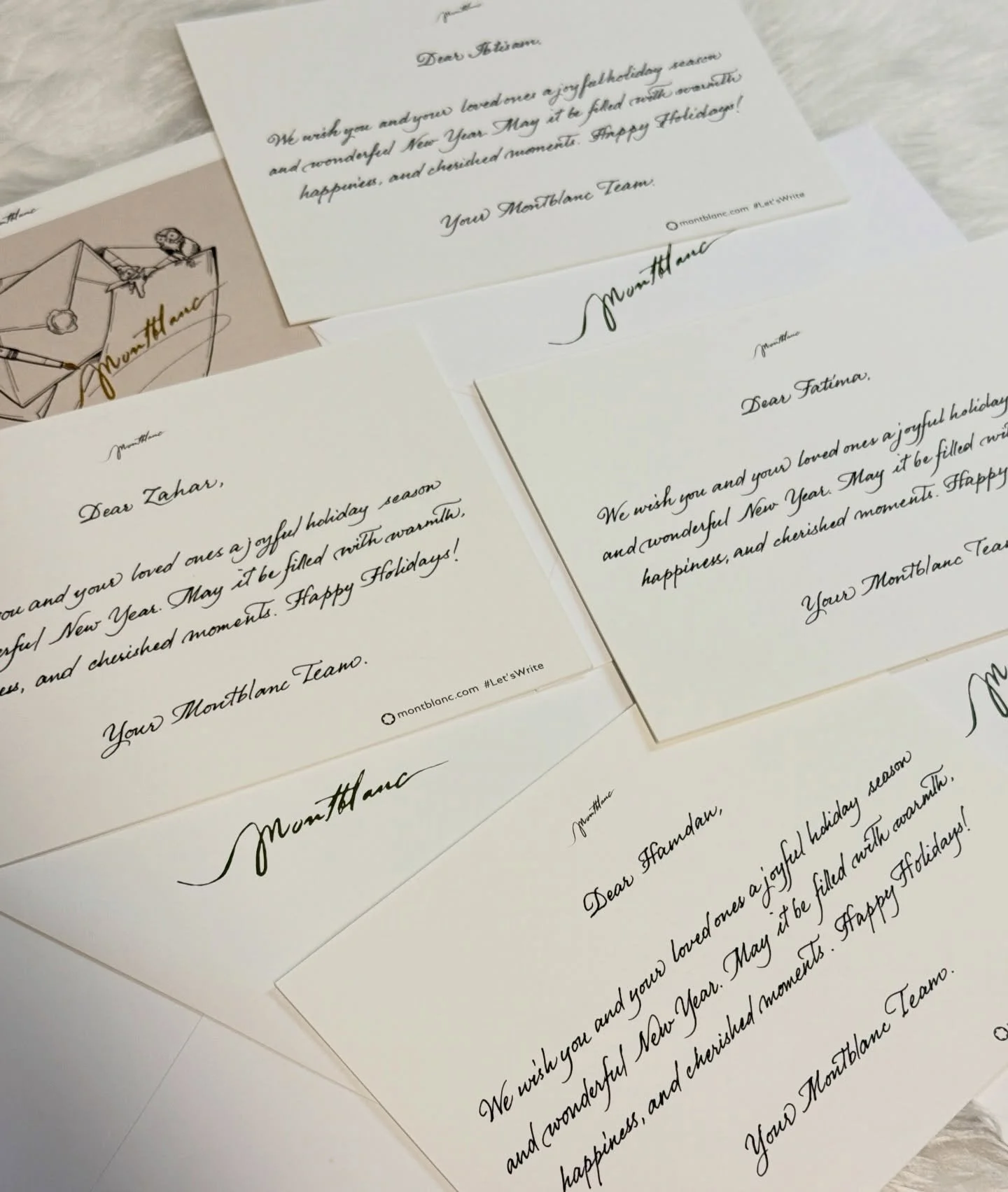 Several handwritten holiday greeting cards with cursive and print text, some featuring illustrations of a letter and a Christmas ornament, spread out on a light surface.