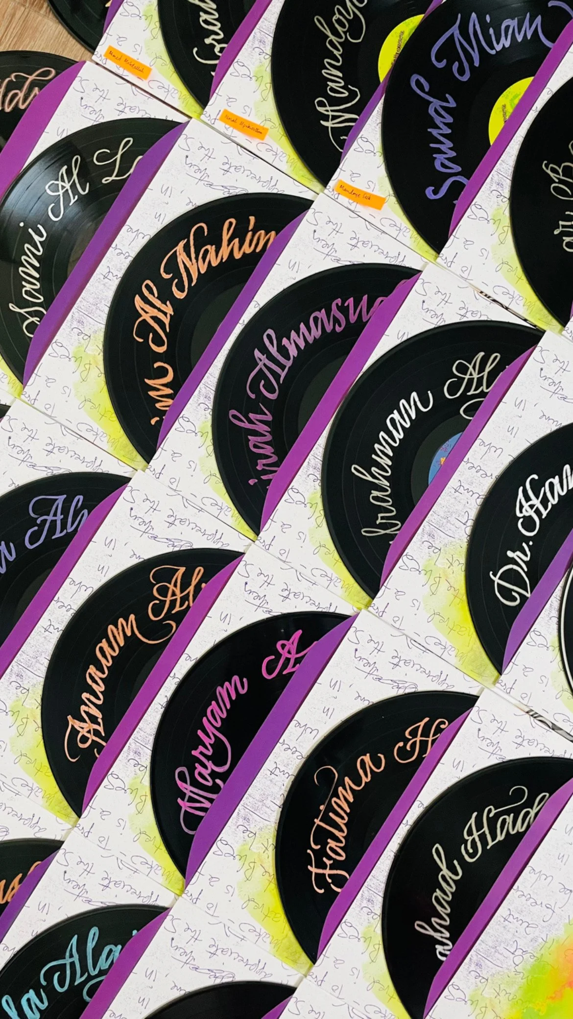 Close-up image of multiple printed materials featuring a black circular graphic with the phrase 'Ala Ham' in colorful cursive text, arranged in a repeating pattern with handwritten notes in the background.
