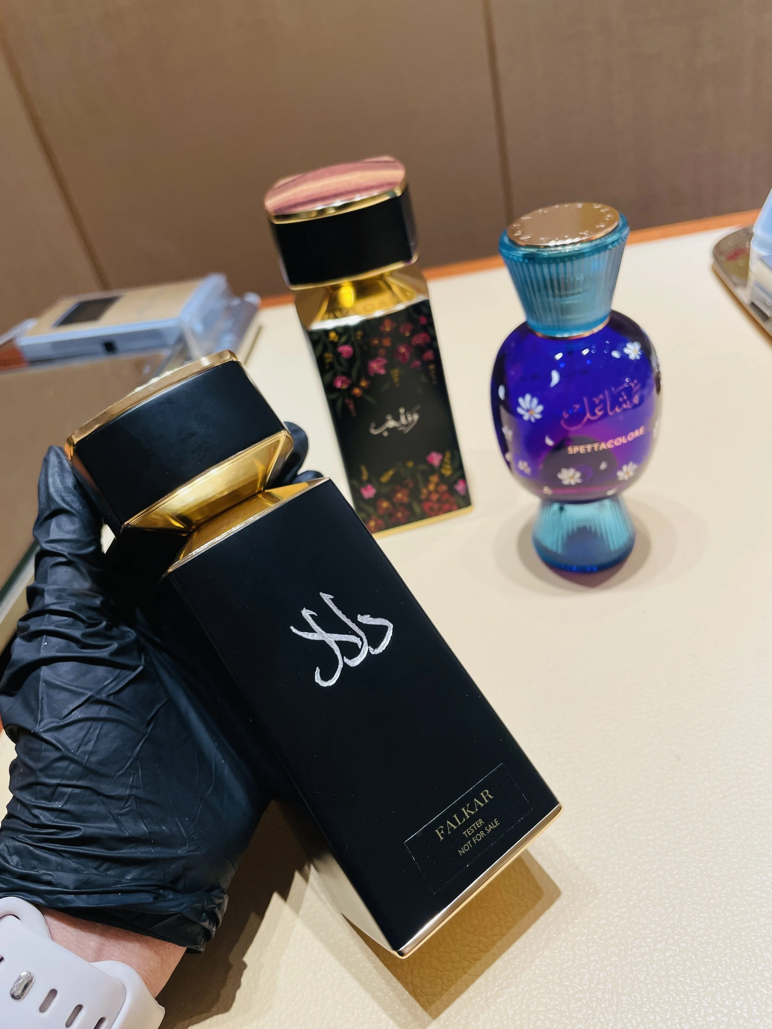 Close-up of a hand in a black glove holding a black box of Falkar tester perfume, with the label "NOT FOR SALE".