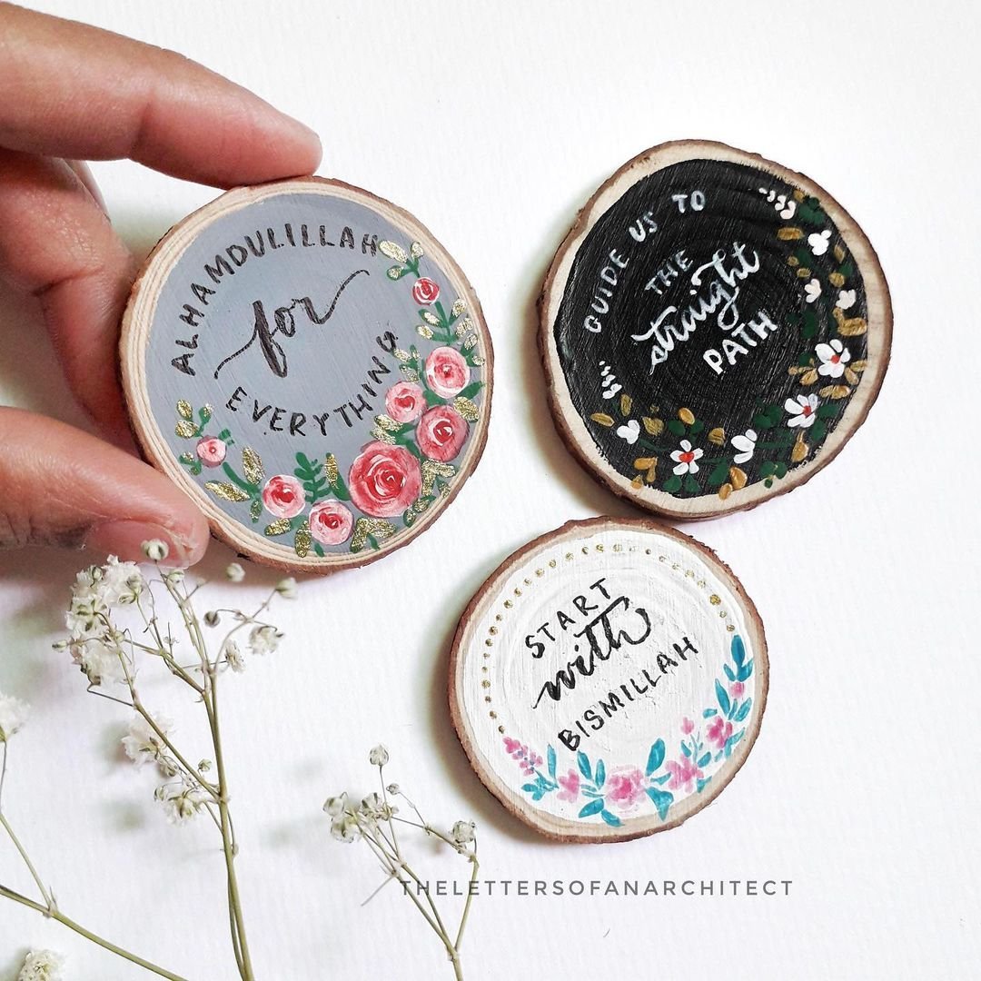 Decorative wooden discs with inspirational quotes, floral designs, and colorful accents on white background.