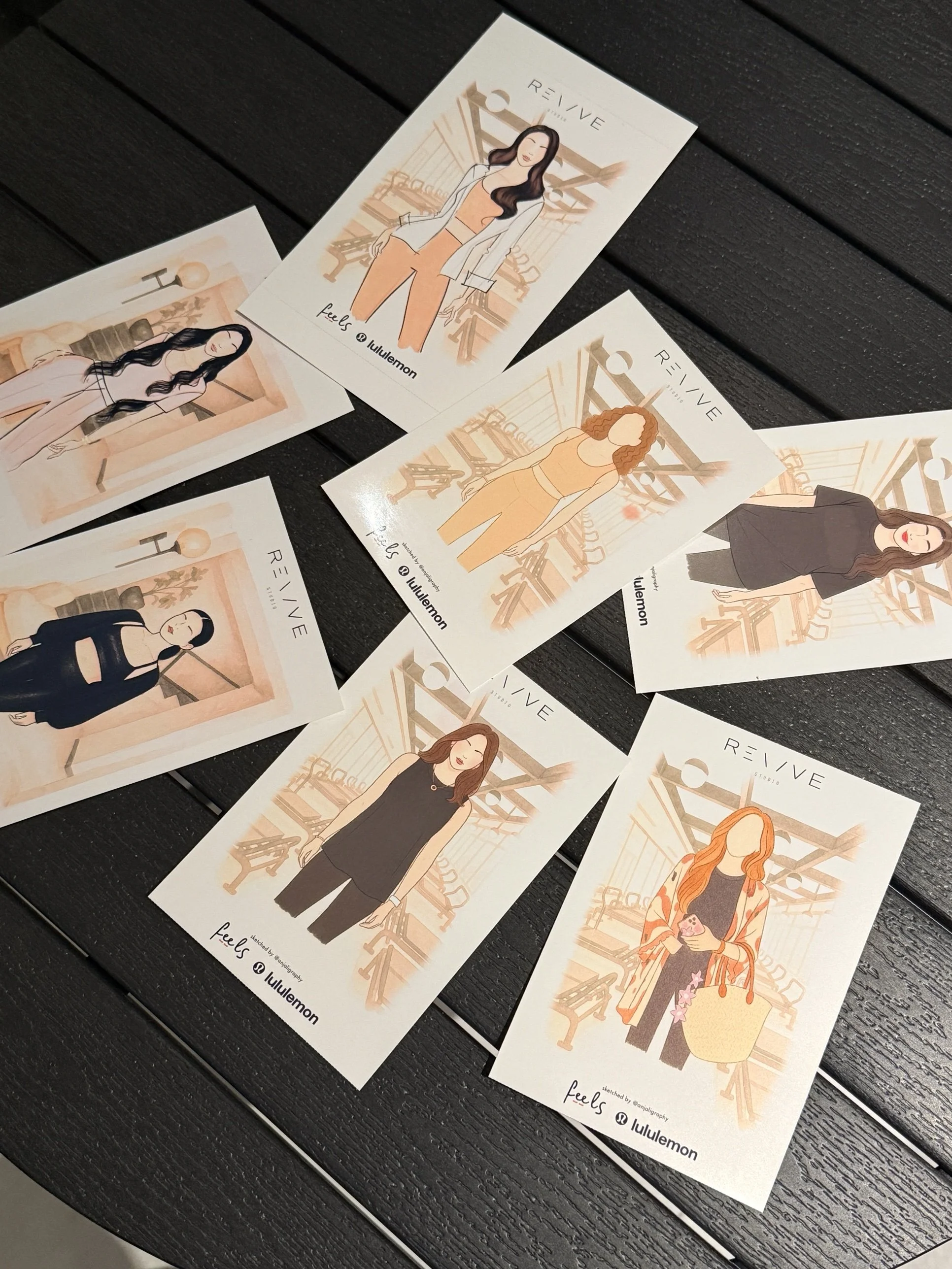 A collection of illustrated cards featuring diverse women in various outfits, positioned on a dark wooden surface.