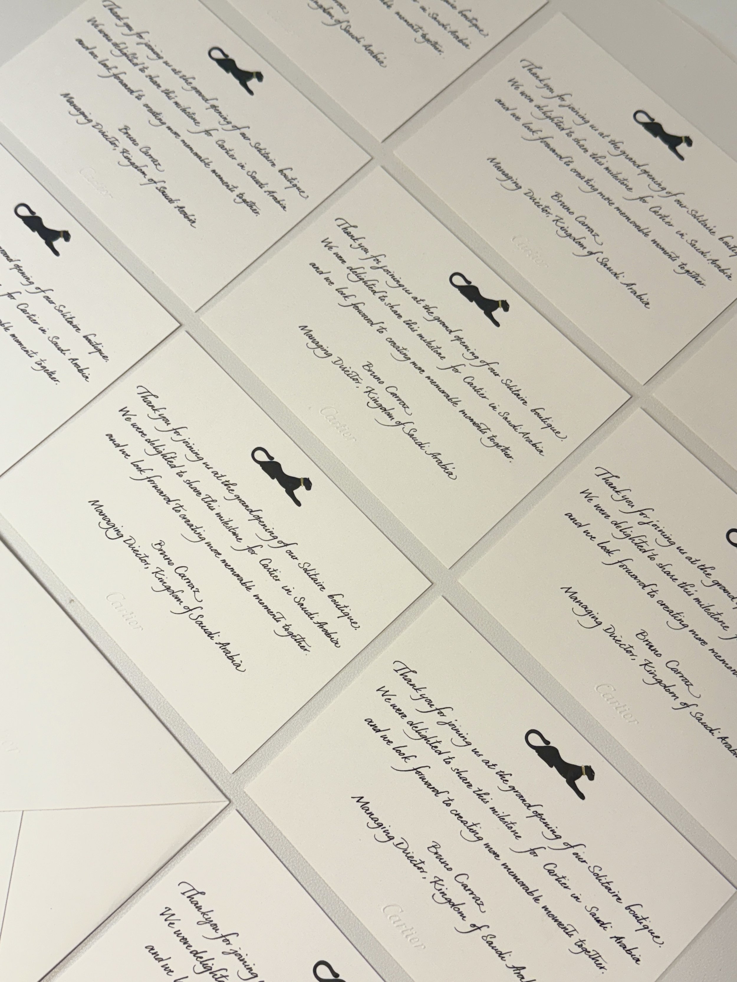 Close-up of several white greeting cards with black dachshund silhouettes and cursive writing, placed on a white surface.