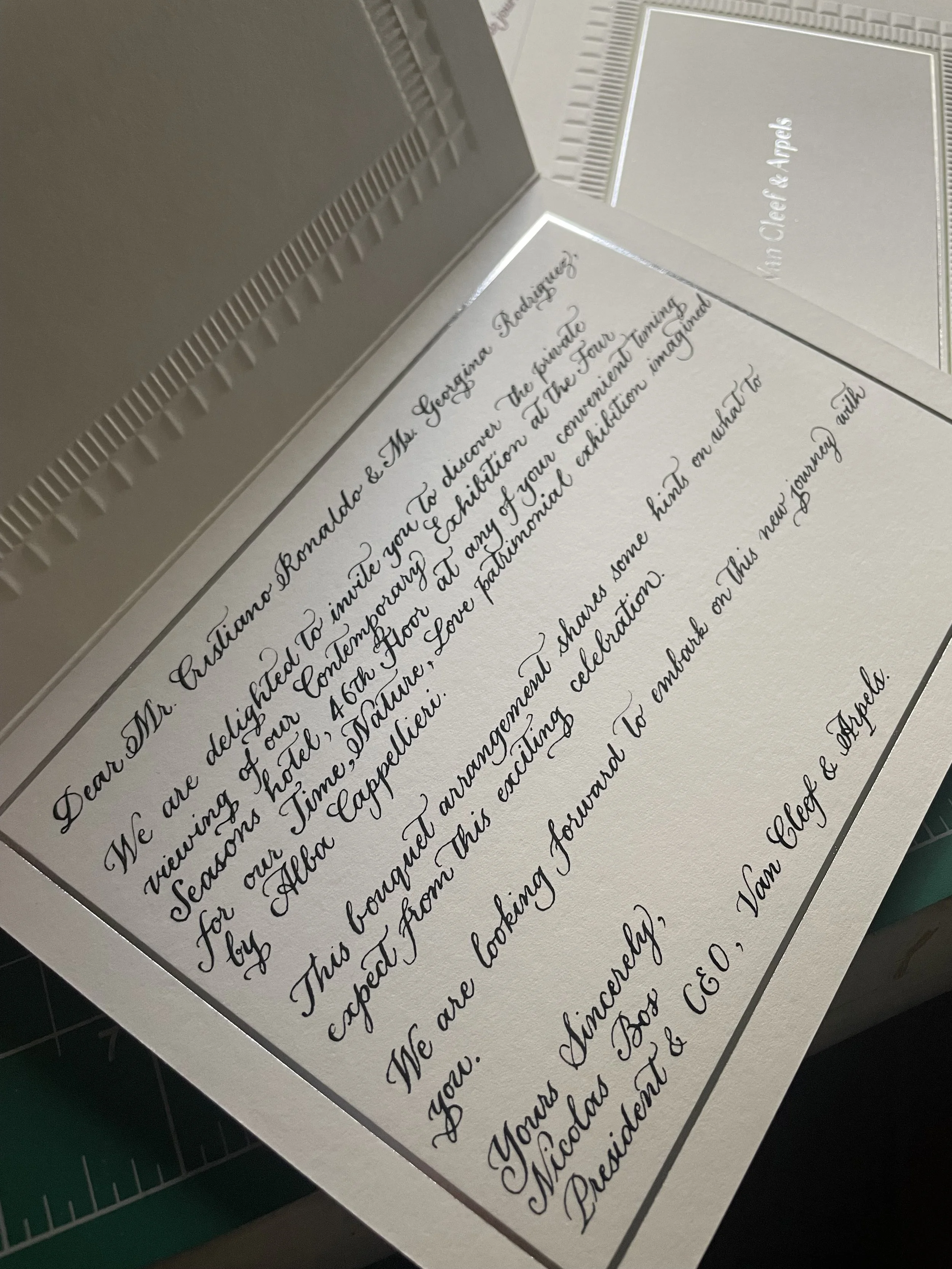 Close-up of a handwritten letter on white paper with cursive script, partially visible, placed on a cutting mat.