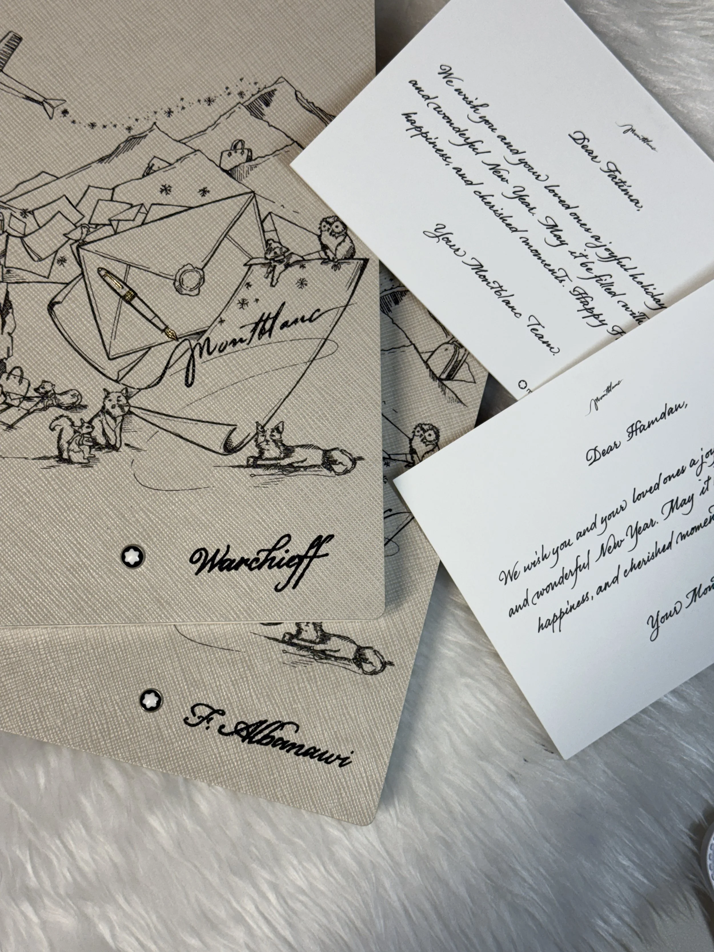 A greeting card with a sketch of a mountain, an owl, and animals, alongside a handwritten note on white paper with elegant cursive text.