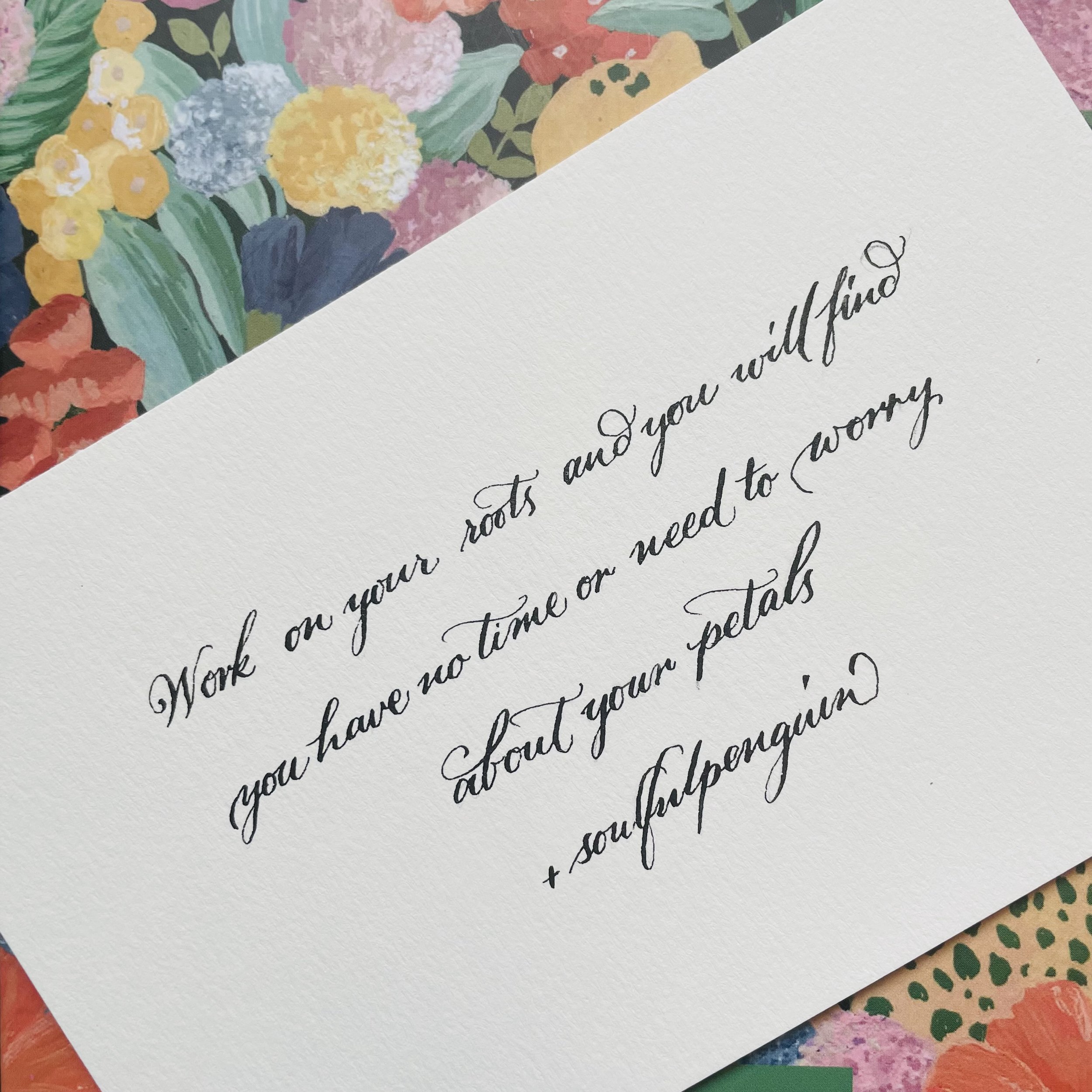 Close-up of a handwritten letter on textured white paper layered on top of a colorful floral and patterned paper.