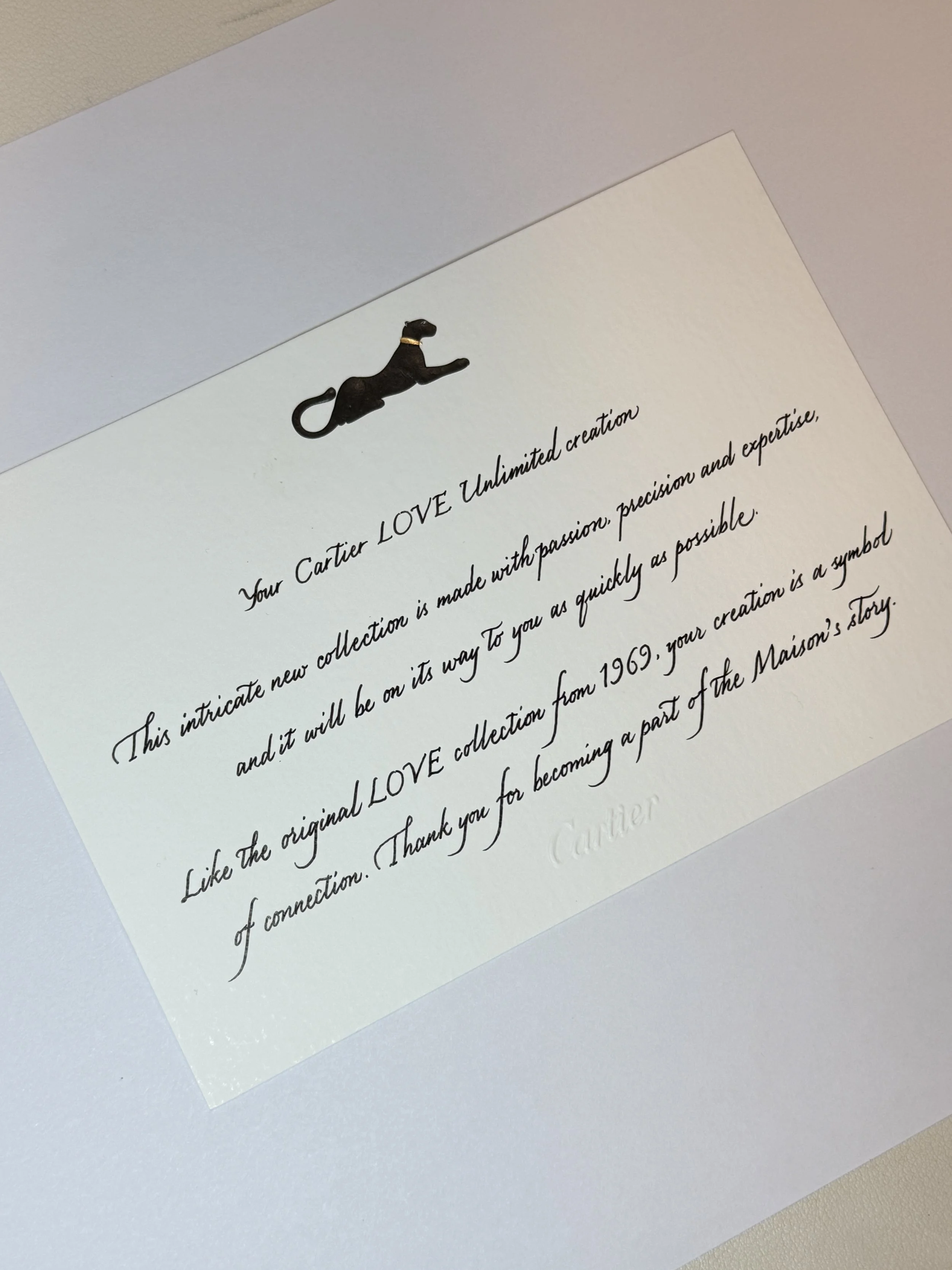 Close-up of a white paper with black cursive text and a small black dog with a gold collar illustration at the top.