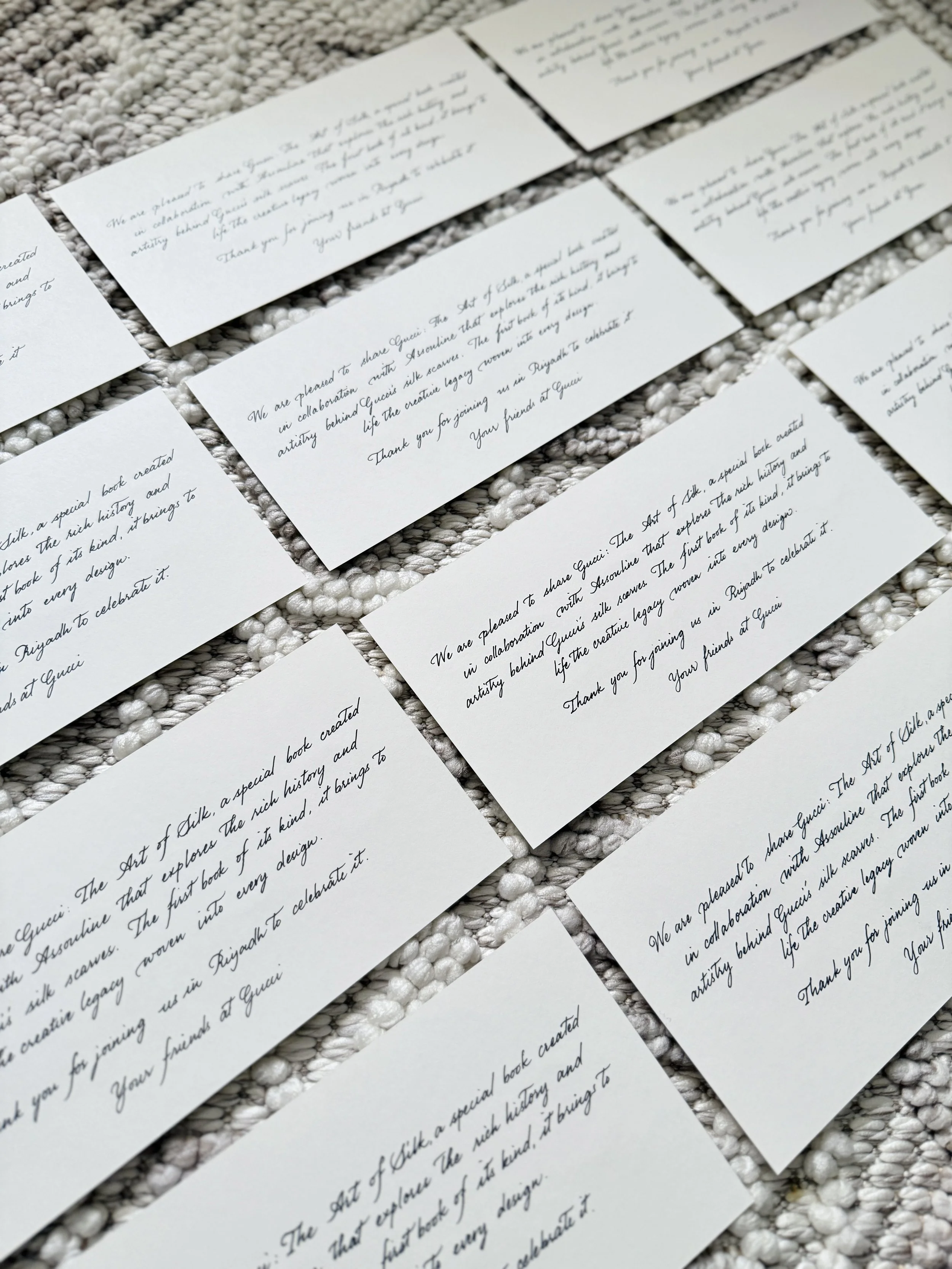 Multiple white paper cards arranged on a textured surface with handwritten text on each card.
