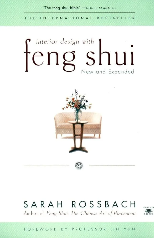 Couverture du livre intitulé 'Interior Design with Feng Shui' de Sarah Rossbach, avec une image d'un canapé beige, une table en bois avec un bouquet de fleurs dans un vase, et une couverture verte avec des détails en noir.