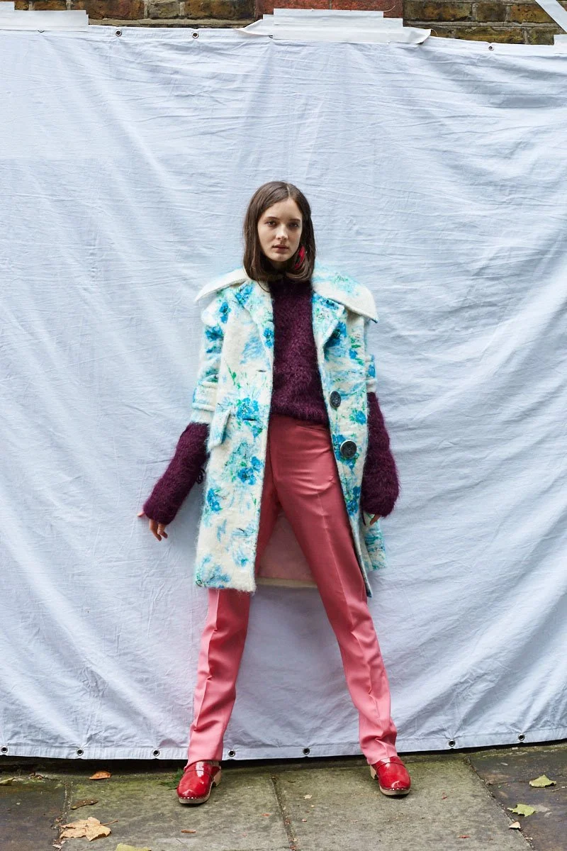 Model in a mix of textures and colours, featuring a blue floral coat and pink trousers, styled by Zoe James.