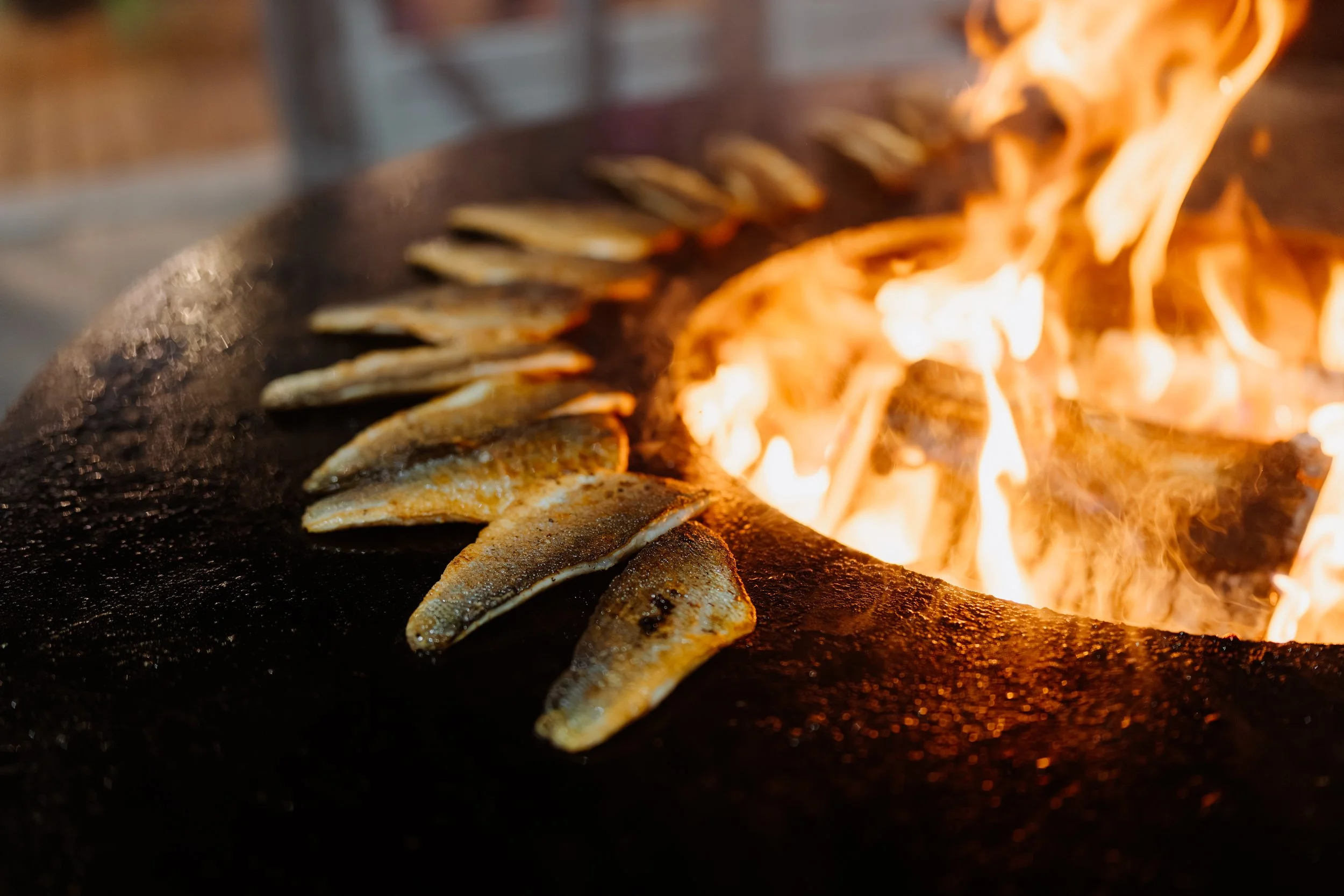 Visfilets worden geroosterd boven een open vuur.