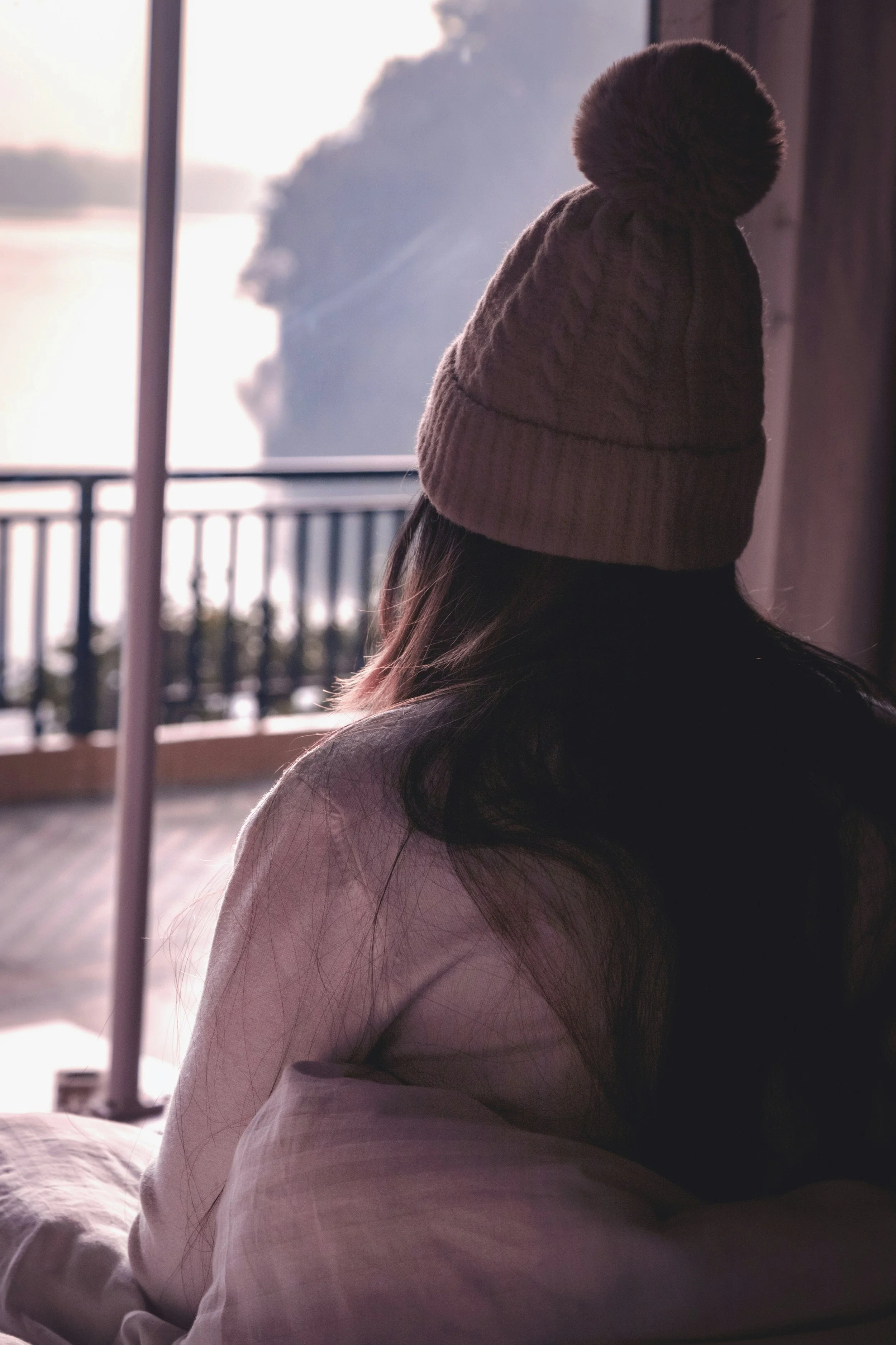 Fatigued woman wearing a hat staring outside reflecting on her exhaustion and her chronic fatigue syndrome