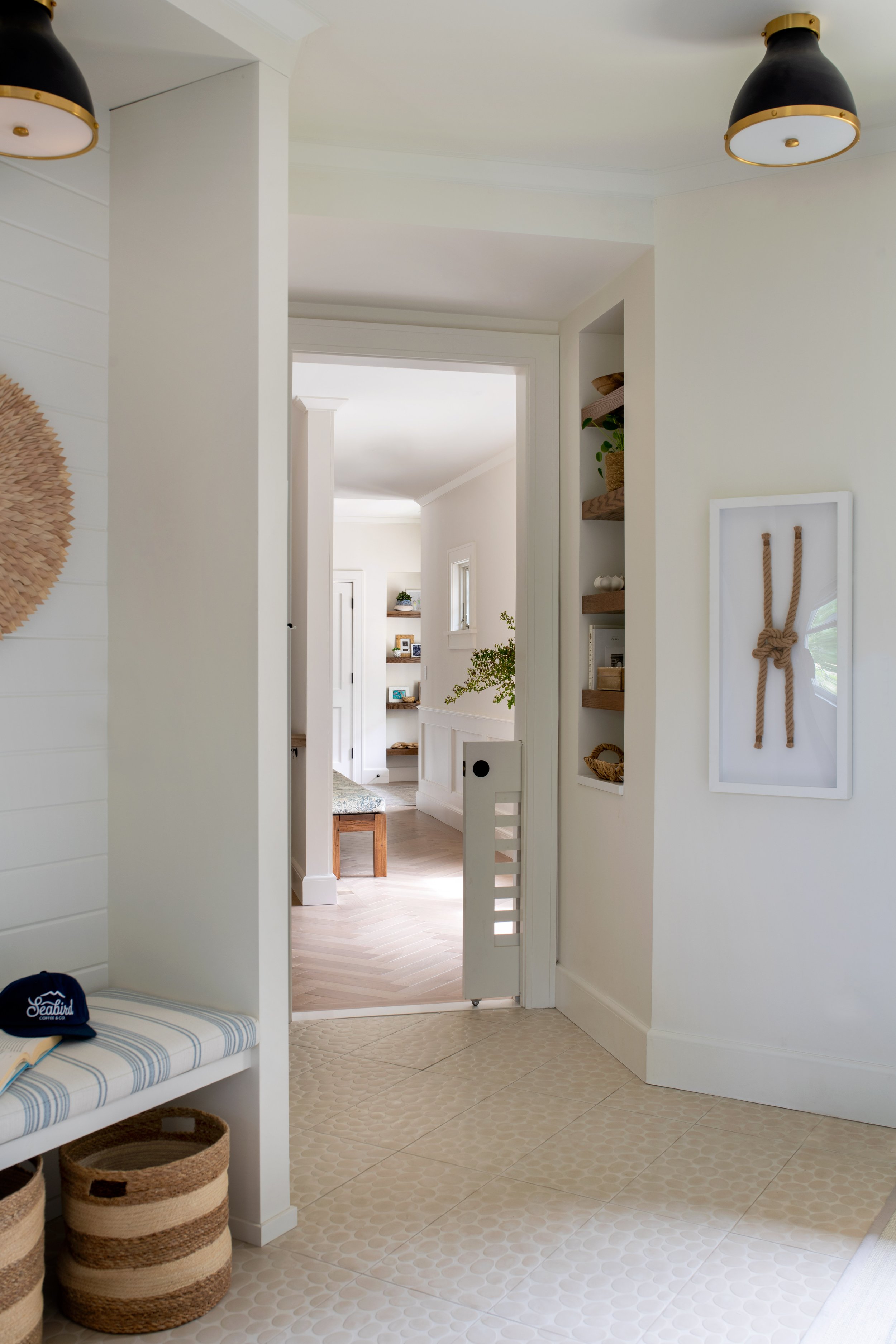 Coastal mudroom with built-in bench, cleanable floor tile, and a built-in dog gate.