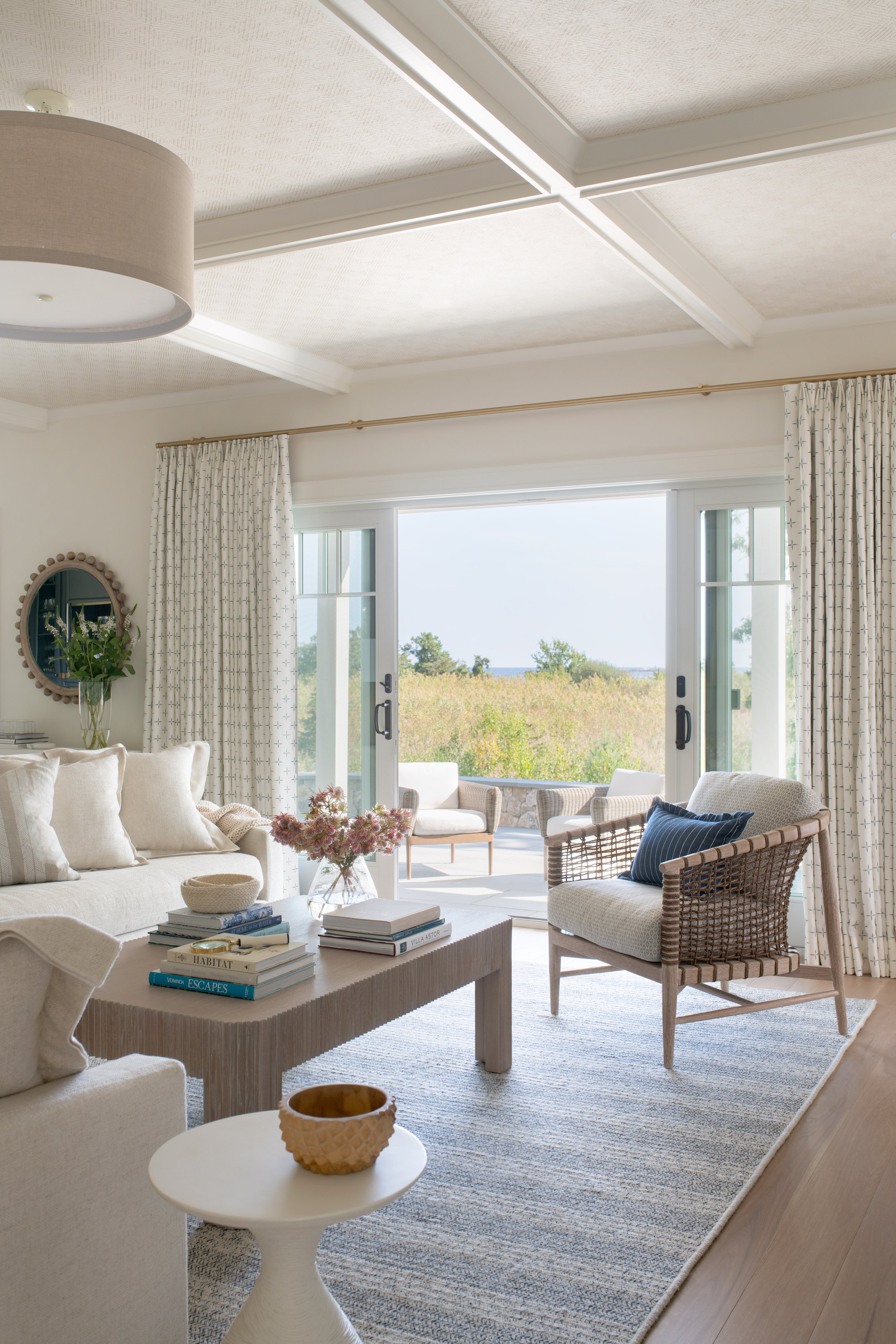 Coastal living room with an accent chair, neutral rug, large sliding doors, and drapery.