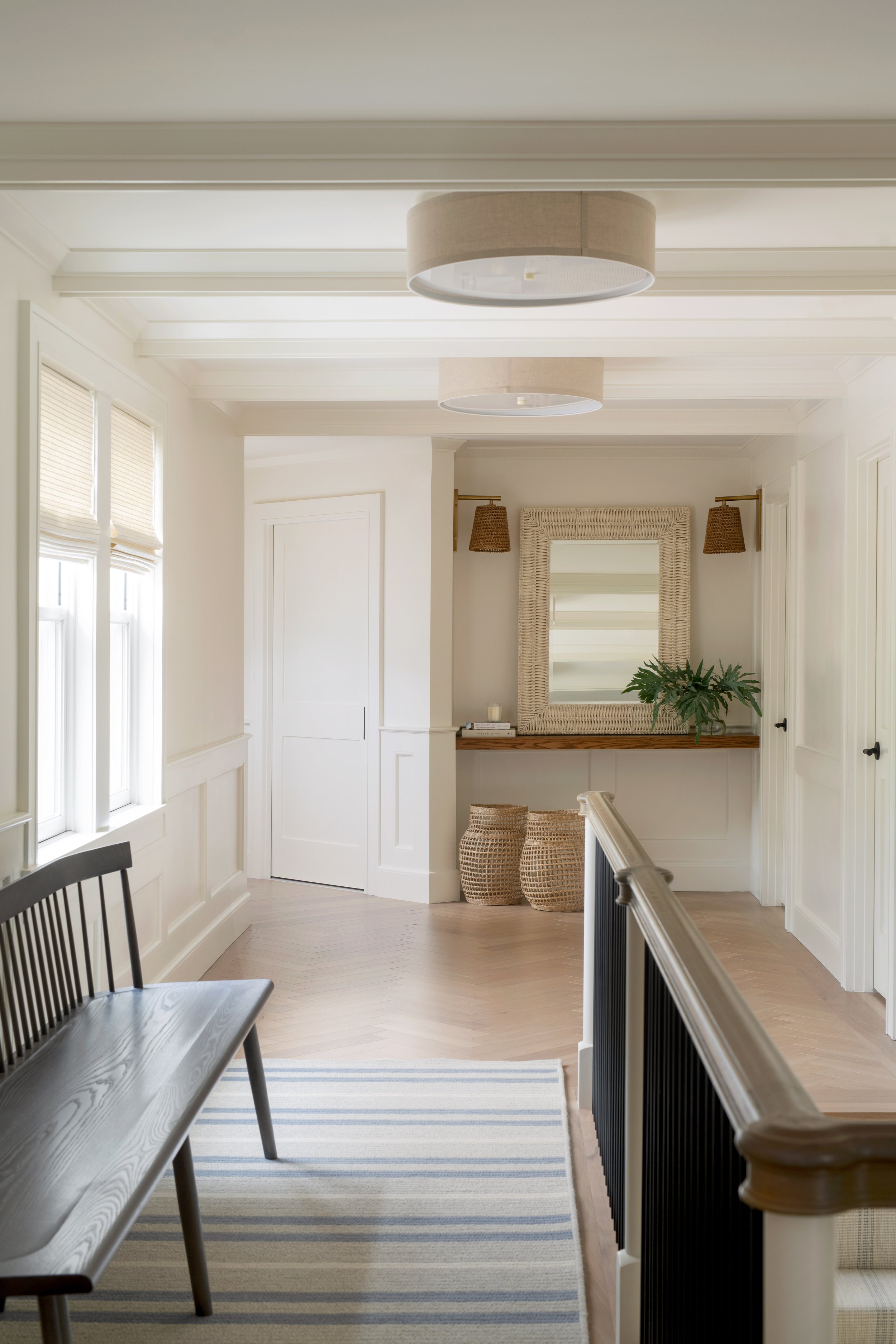 Coastal hallway with a traditional wood bench, cream flush-mounts, and textured wall sconces above a floating wood shelf.