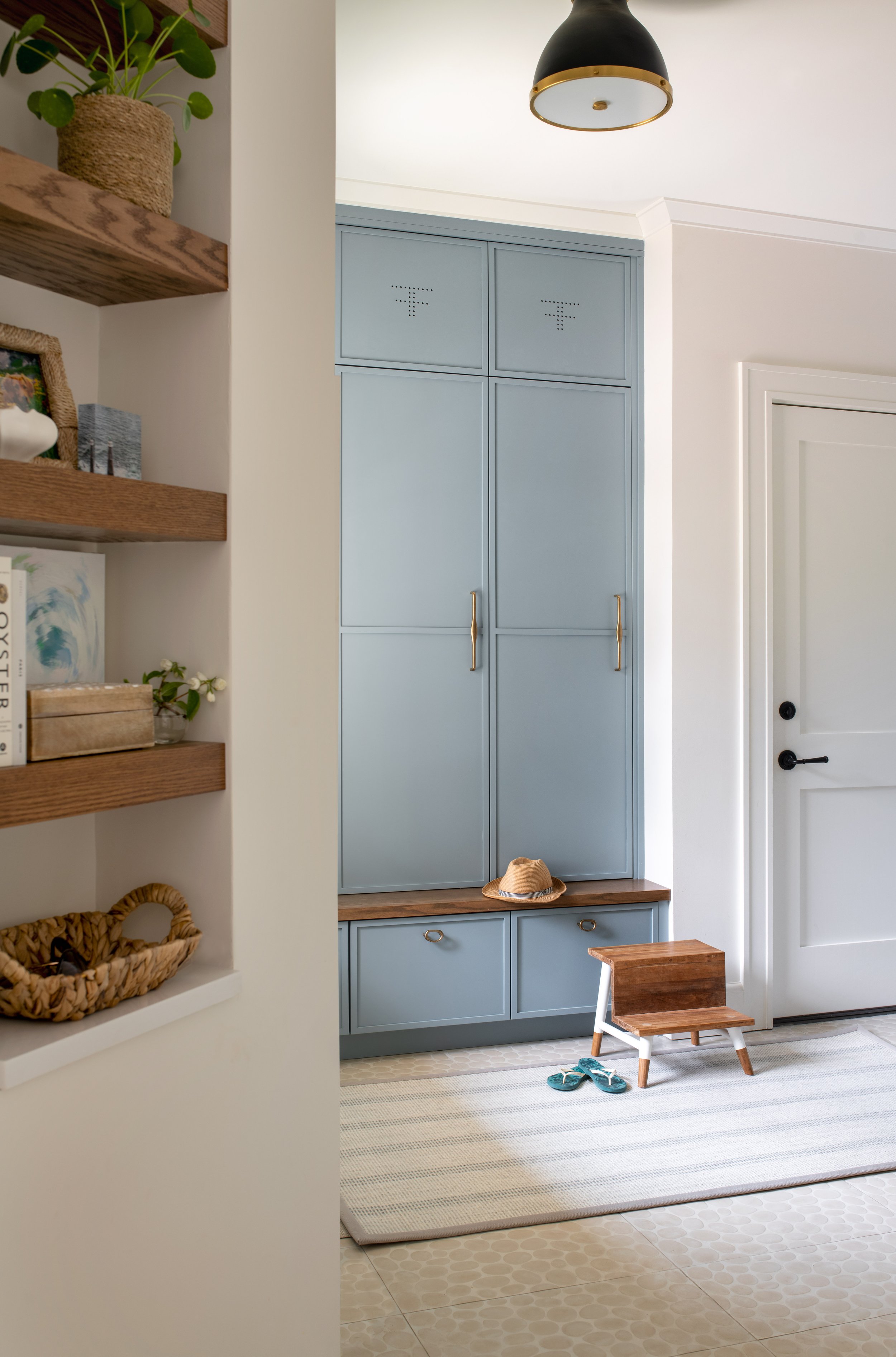 Coastal mudroom storage cabinets with custom ventilation and wood bench seat for ease of taking off and on shoes. Cleanable floor tile.