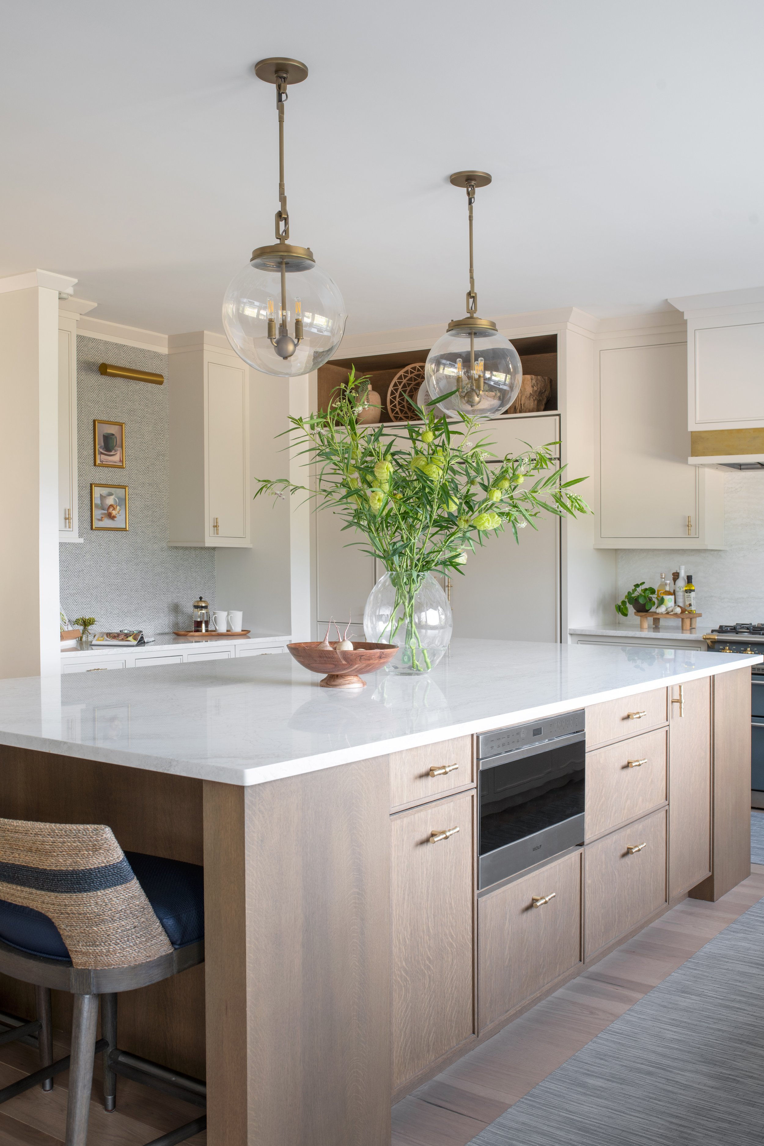 Coastal white kitchen with a natural wood island, navy counter stools, and brass accents.