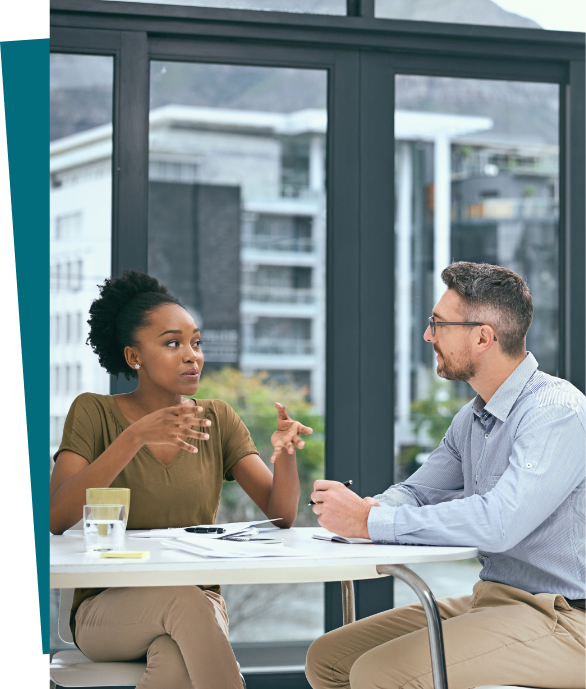 Woman and man sitting at a table talking at work